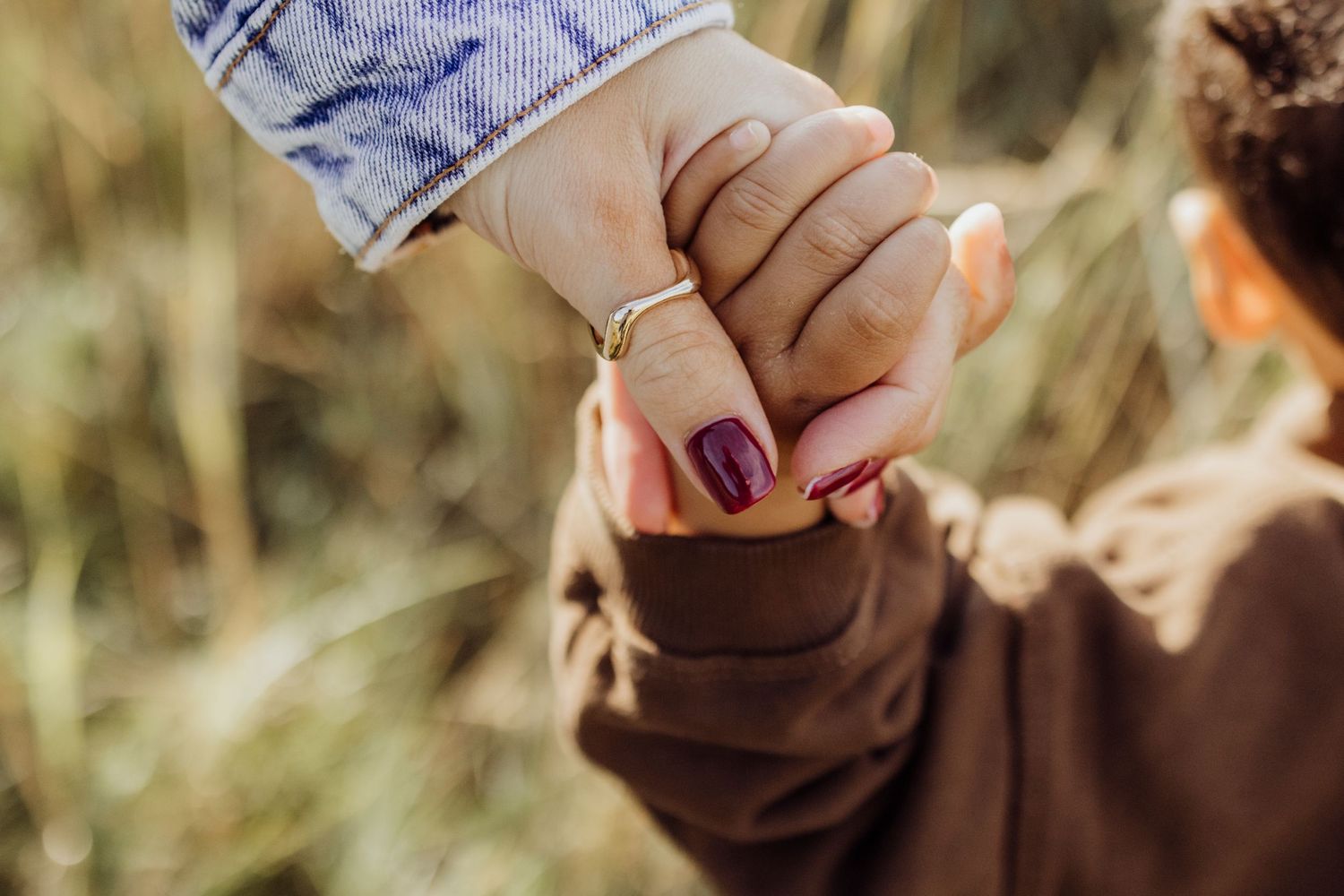 Close-up detail shot of hands with delicate jewelry in natural lighting.