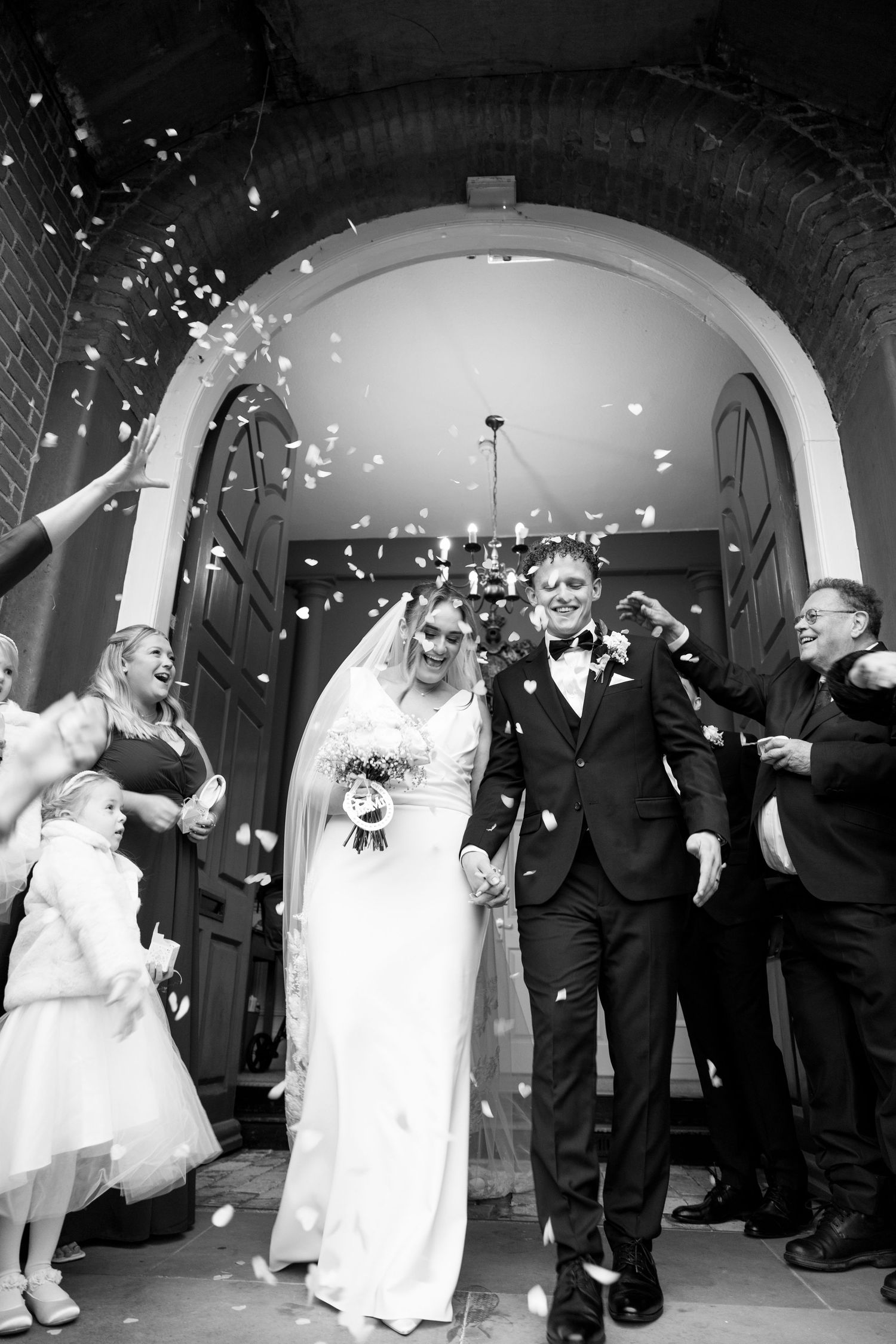 Wedding celebration with confetti falling in arched venue.