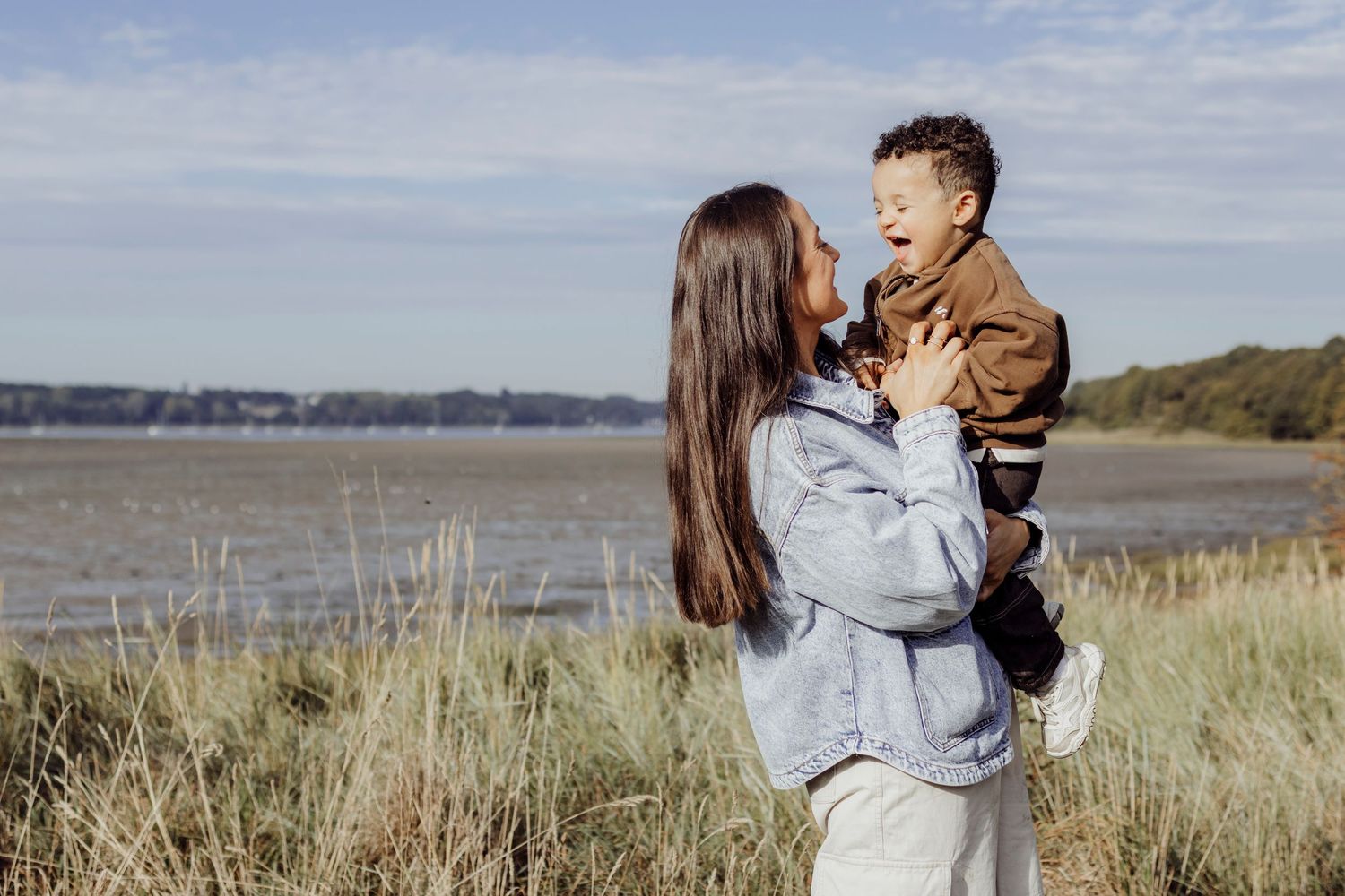 Peaceful scene of people embracing in a coastal meadow with tall grass and blue skies.