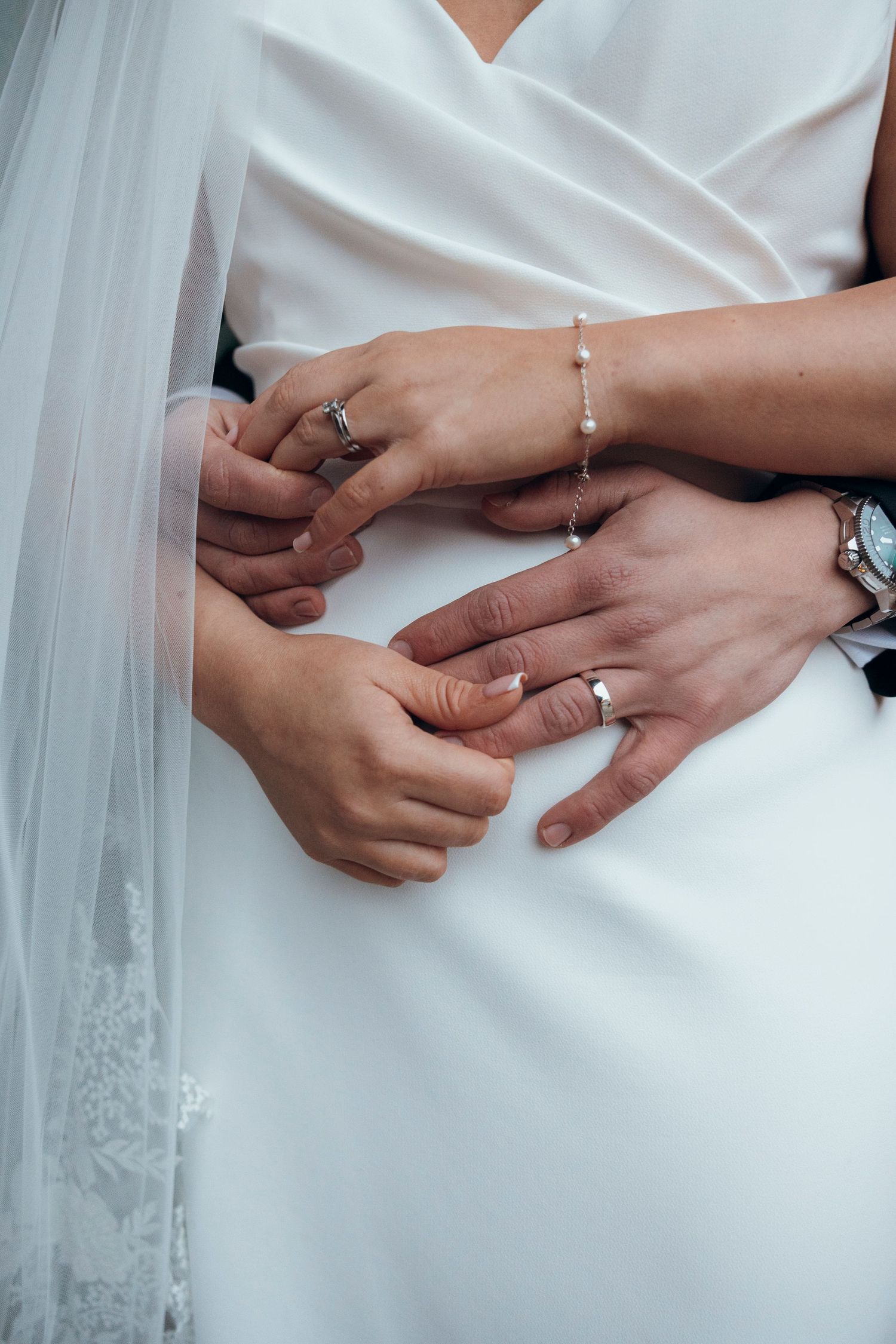 Close-up sequence of hands exchanging wedding rings against white fabric.