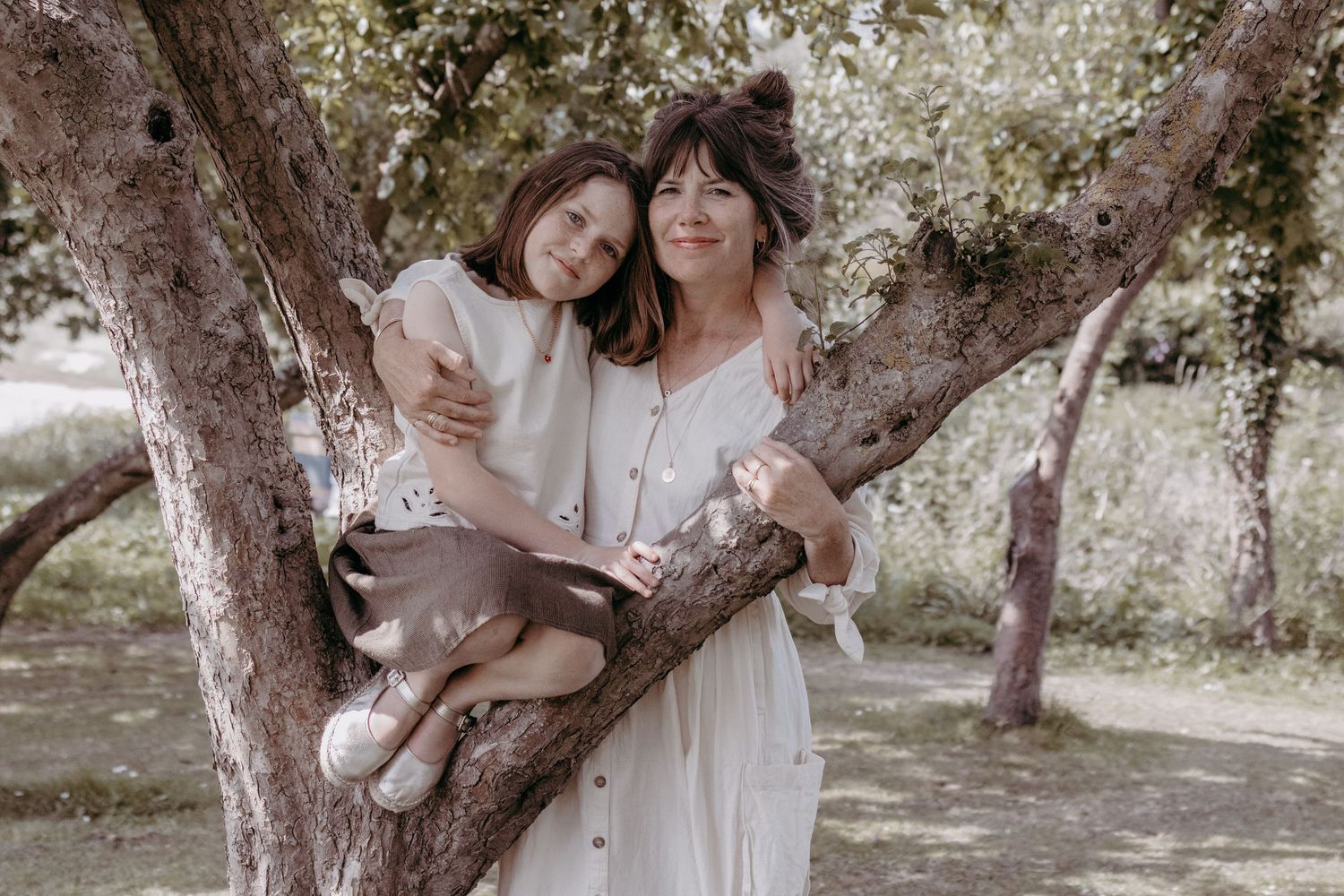 Mother and child share a tender moment while sitting in a blooming tree.