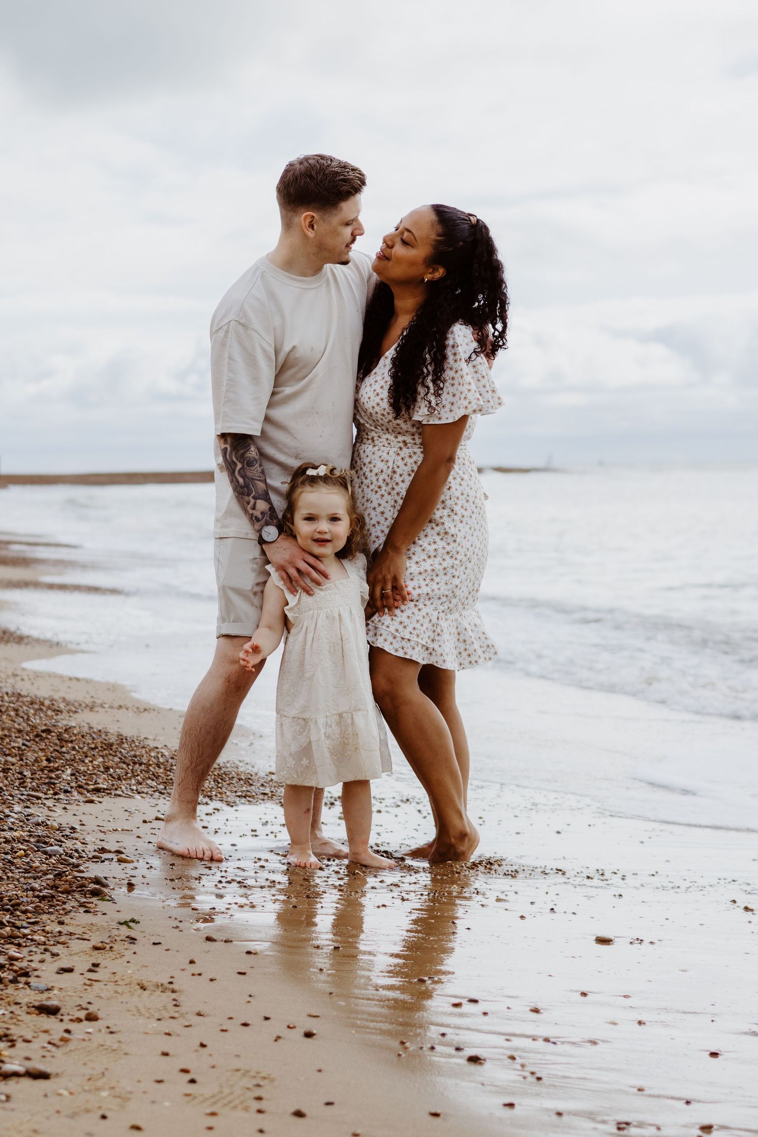 Family shares a loving moment together on a peaceful beach shore.