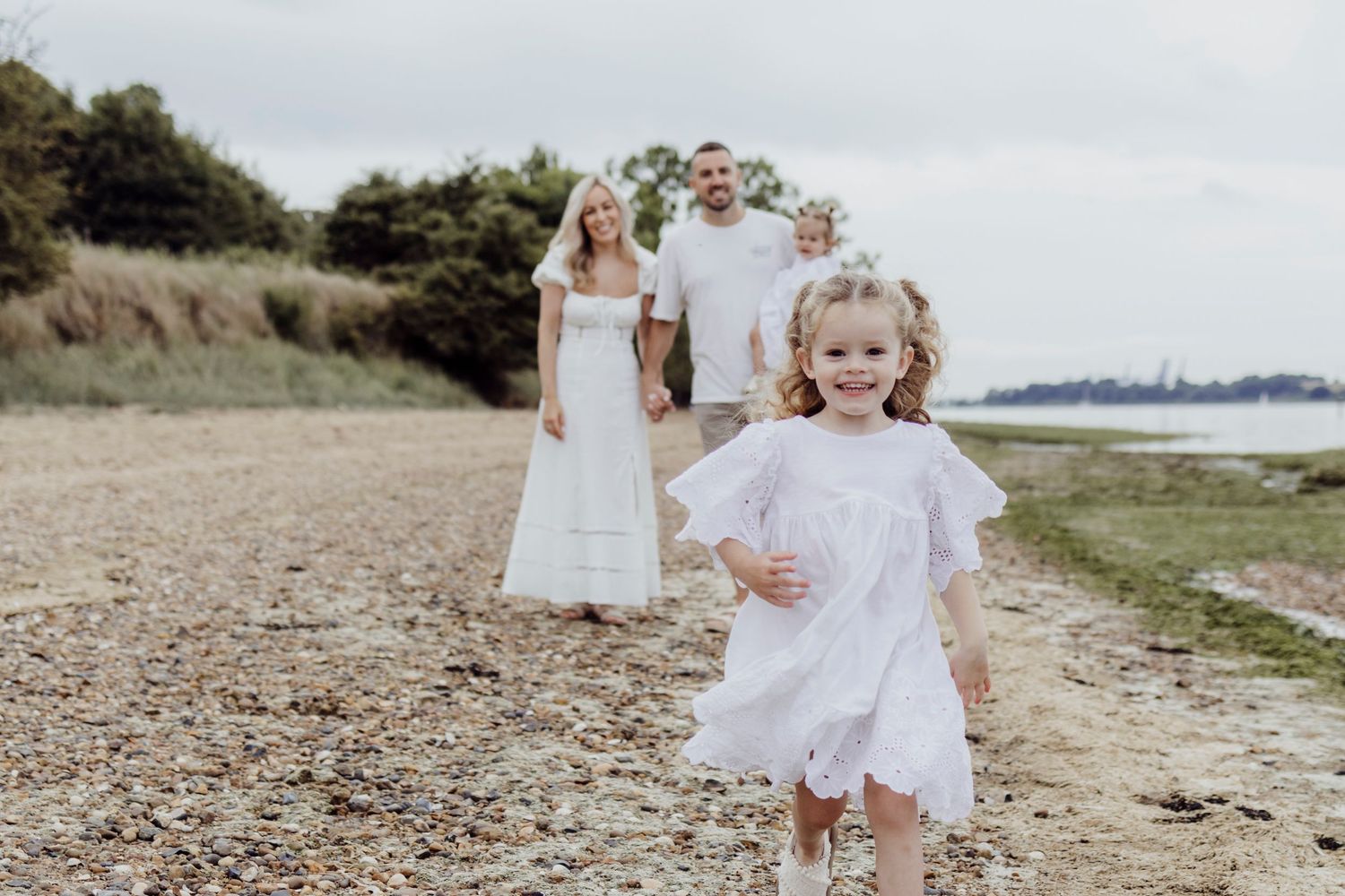 Family walking together along a coastal path on a cloudy day.