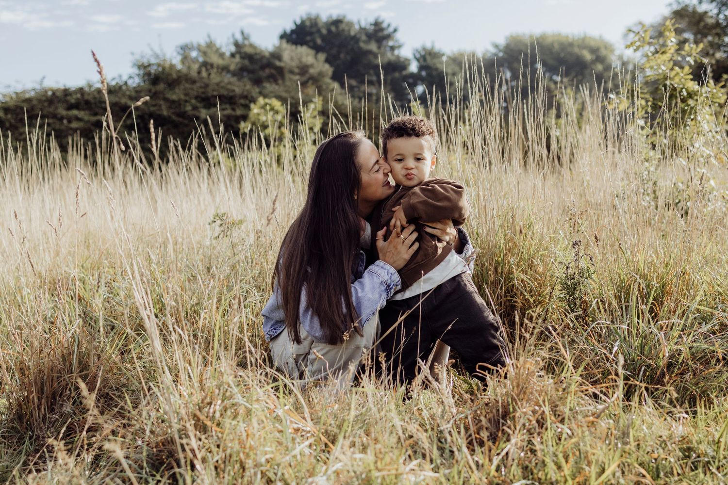 Figures sit together in tall golden grass during a peaceful outdoor moment.