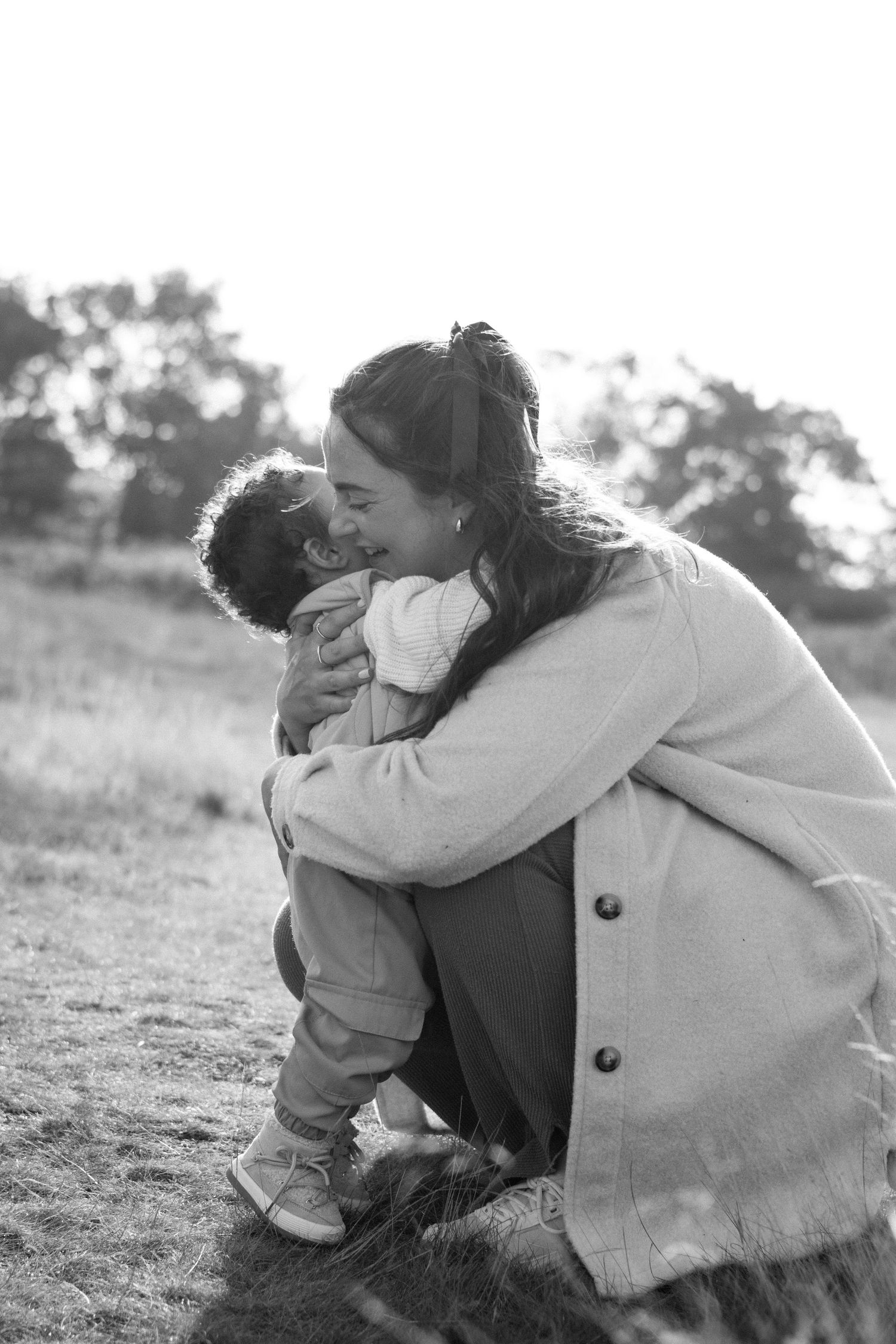 A black and white photograph capturing an emotional embrace between parent and child on a hillside.