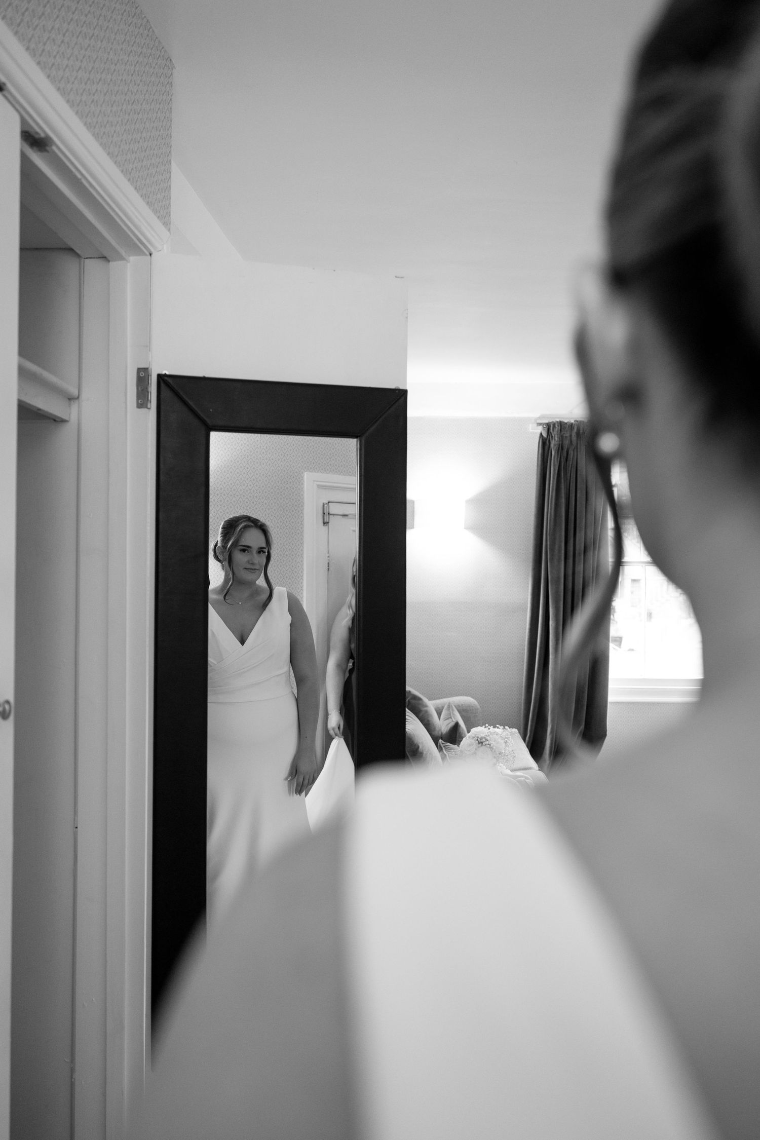 Artistic black and white reflection of a bride looking in a mirror while getting ready.