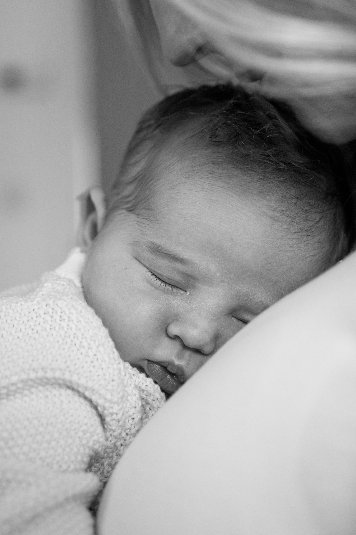 Peaceful black and white close-up of a sleeping infant in polka dot clothing.
