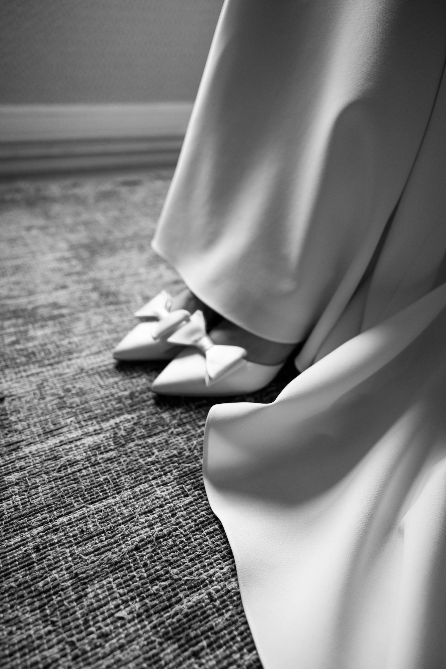 Close-up series of white bridal shoes with delicate bows against a textured carpet.