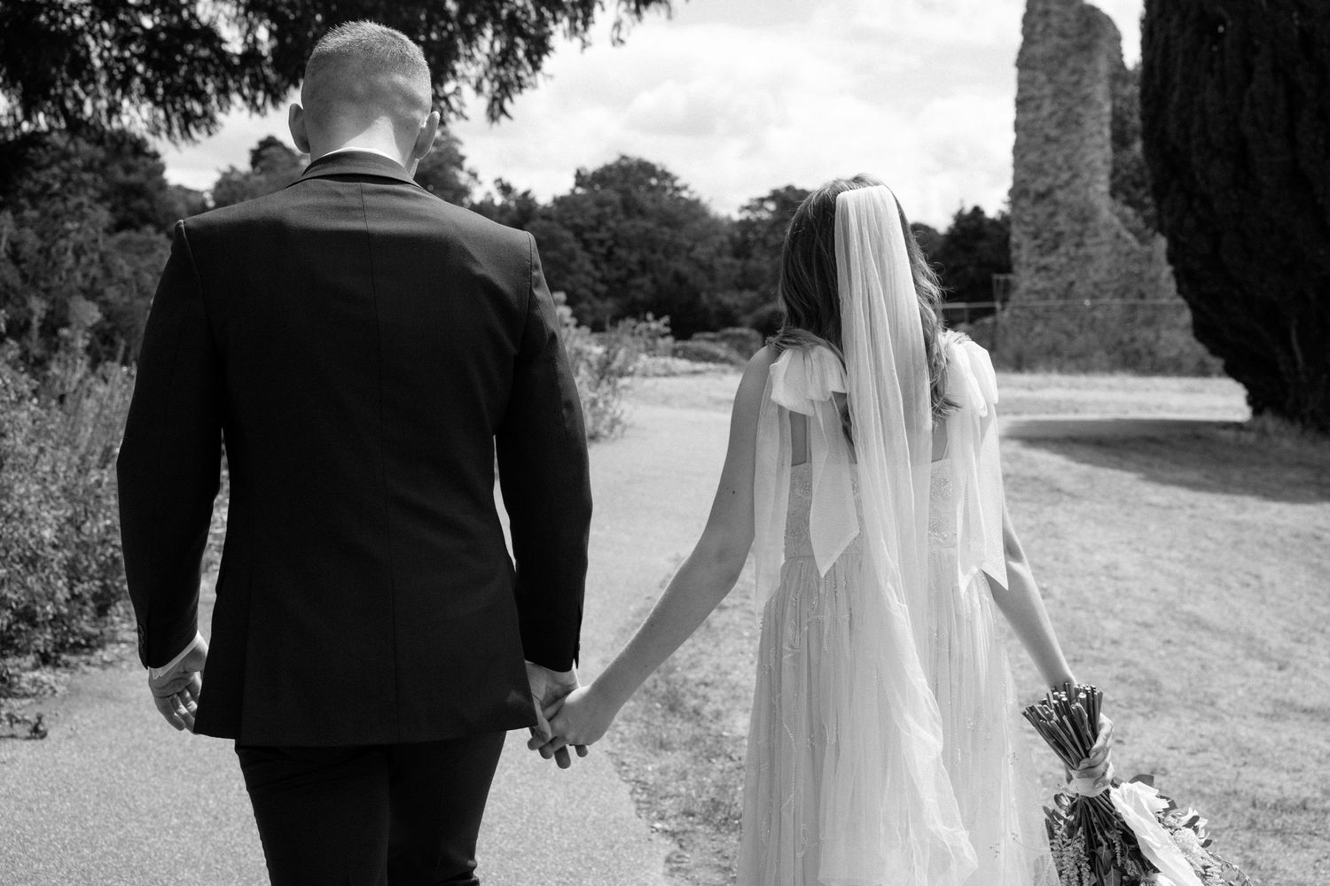 A black and white wedding photo collage showing the bride and groom walking together through scenic outdoor settings.