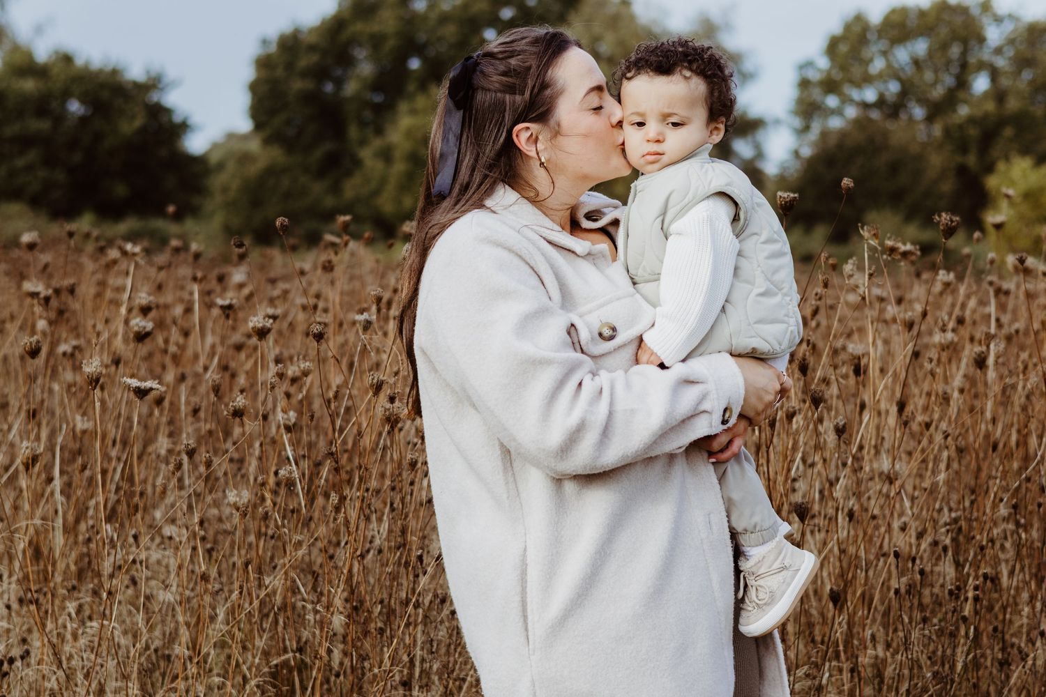 Sweet outdoor family moment captured in a golden field during sunset.