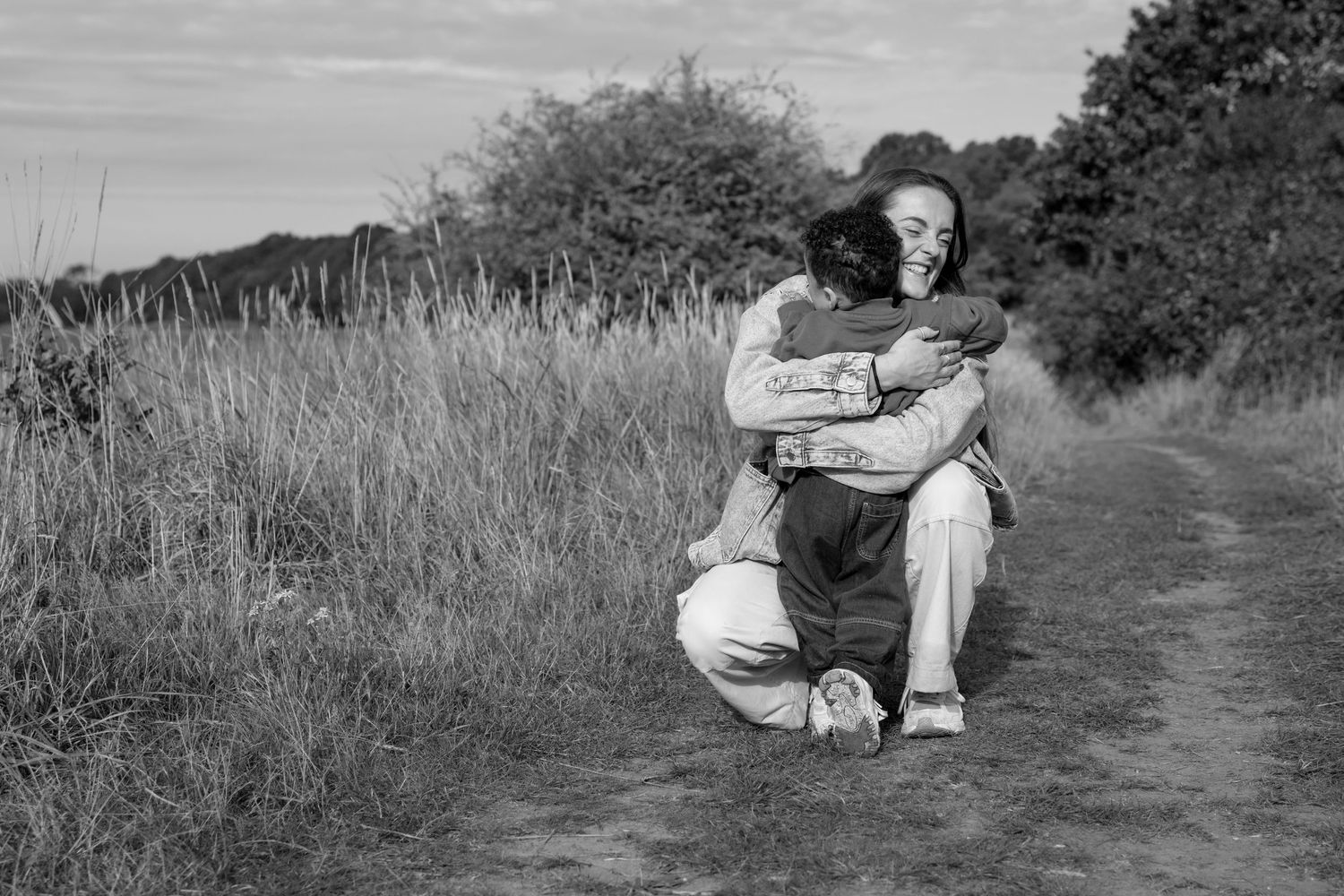 Black and white image of figures sitting together on a grassy hillside path.