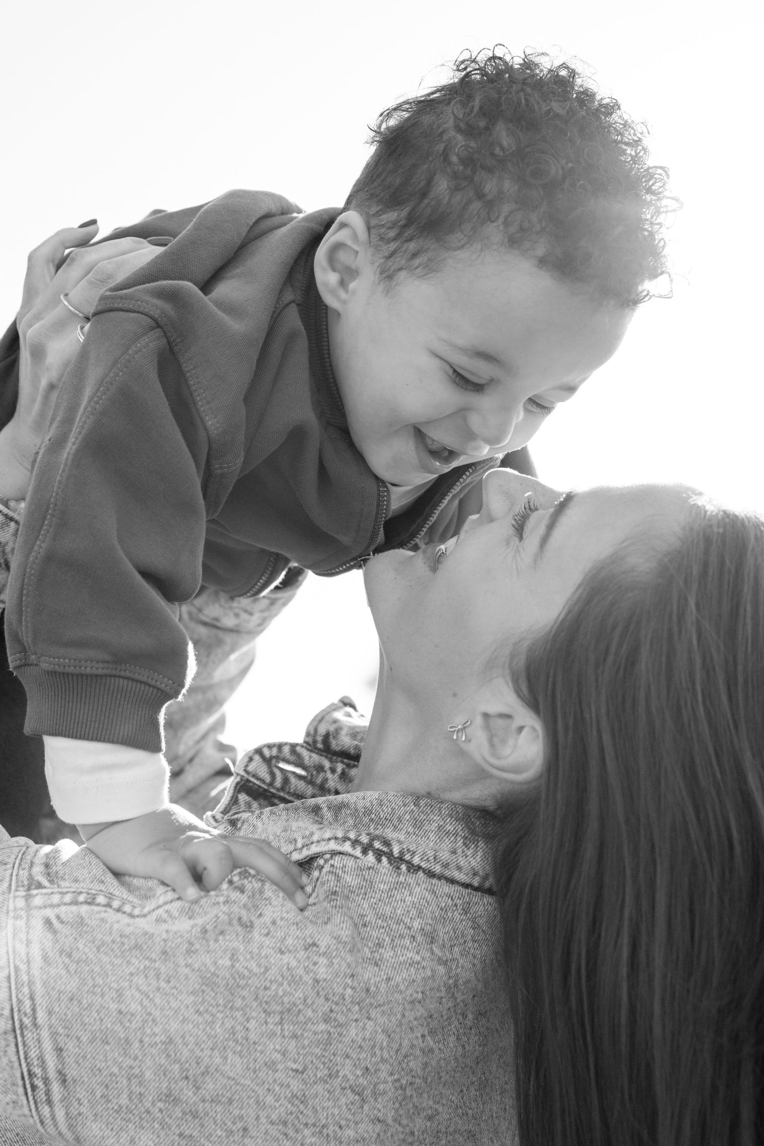 Intimate close-up portraits showing tender family moments against a bright sky.