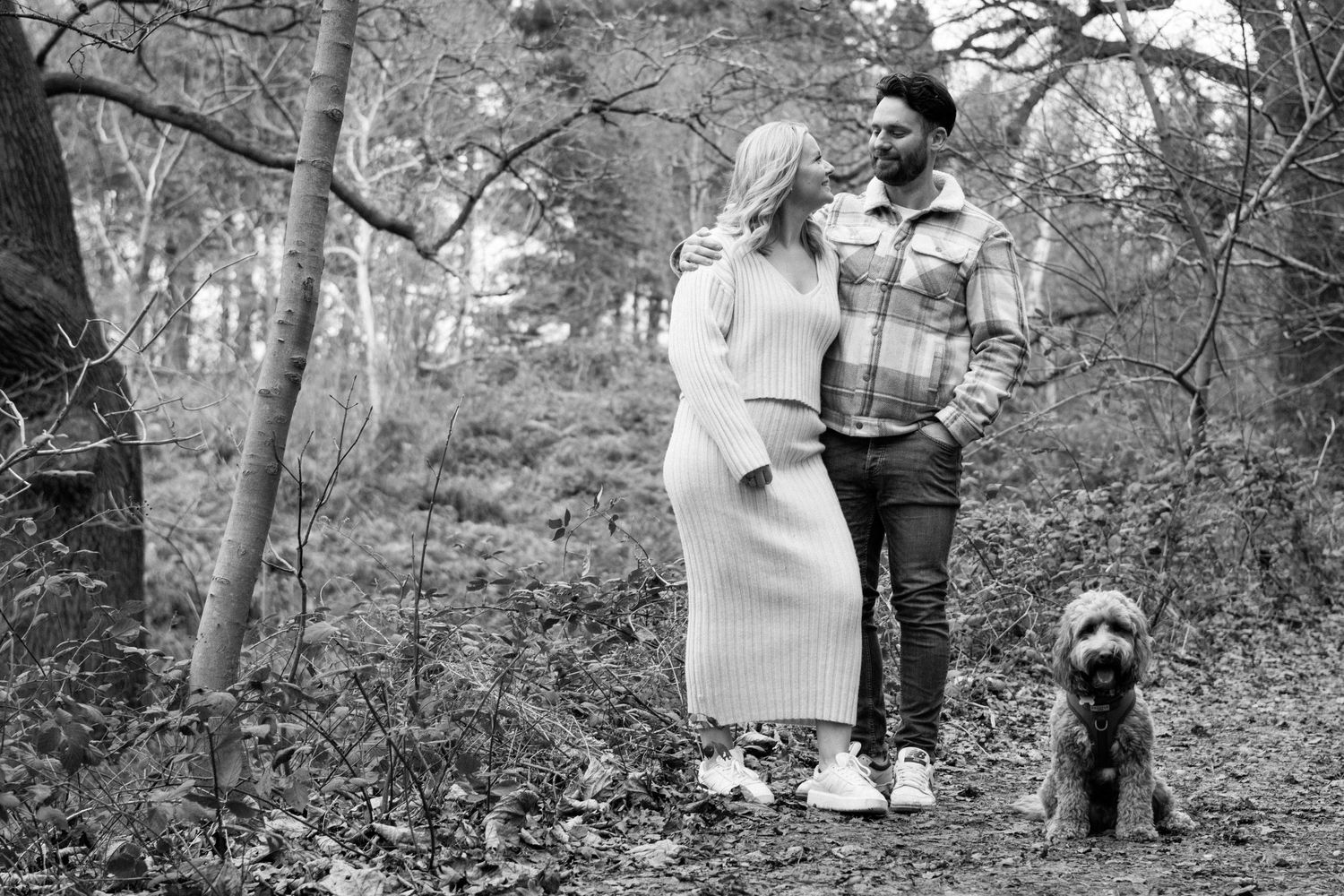 A black and white photo strip showing a group walking through a wooded area with trees and foliage in the background.