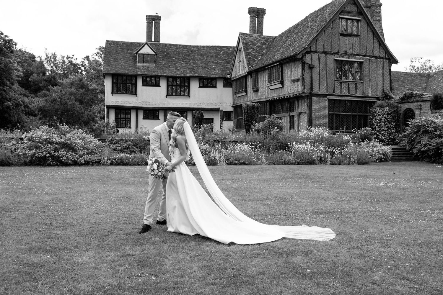 Black and white landscape photos of a rustic house with a long flowing wedding dress in the yard.