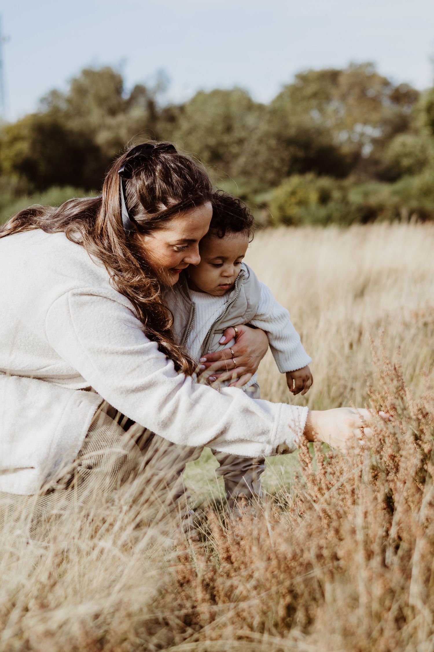 A candid moment of parent and child playing together in a field of tall golden grass.