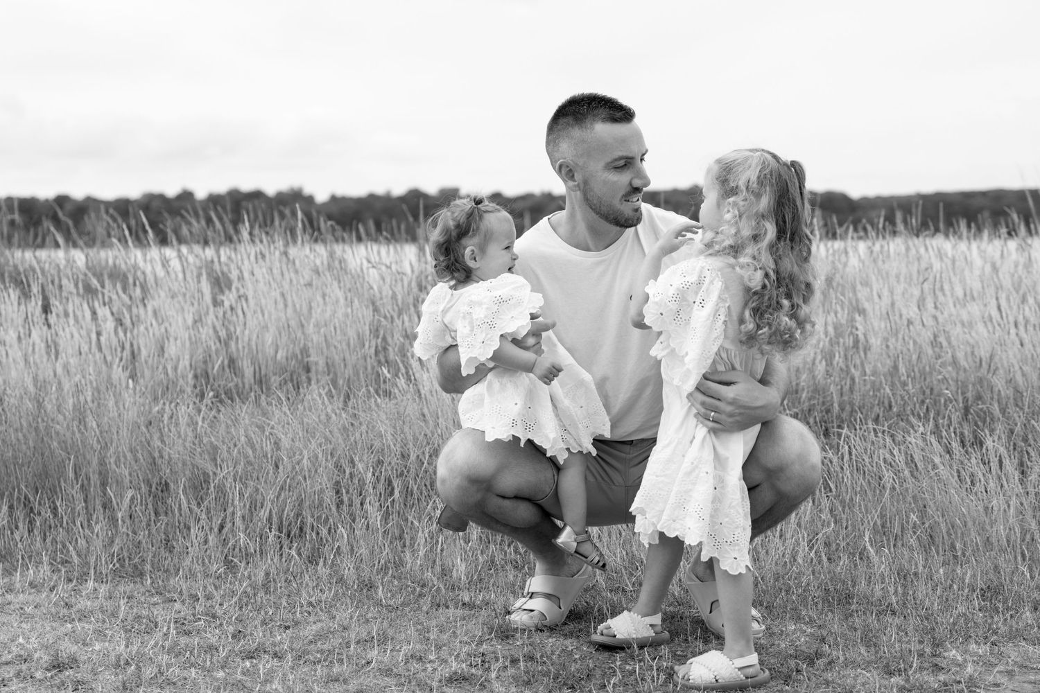 Family shares tender moments together while sitting in a grassy field.