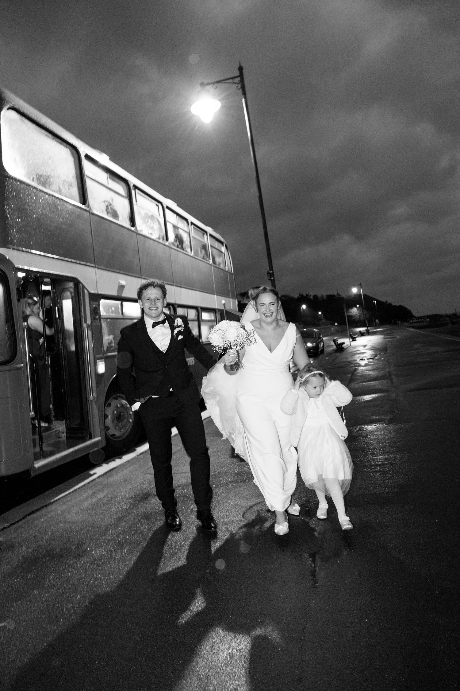 Dramatic black and white photos of people running through rain at night near a train.