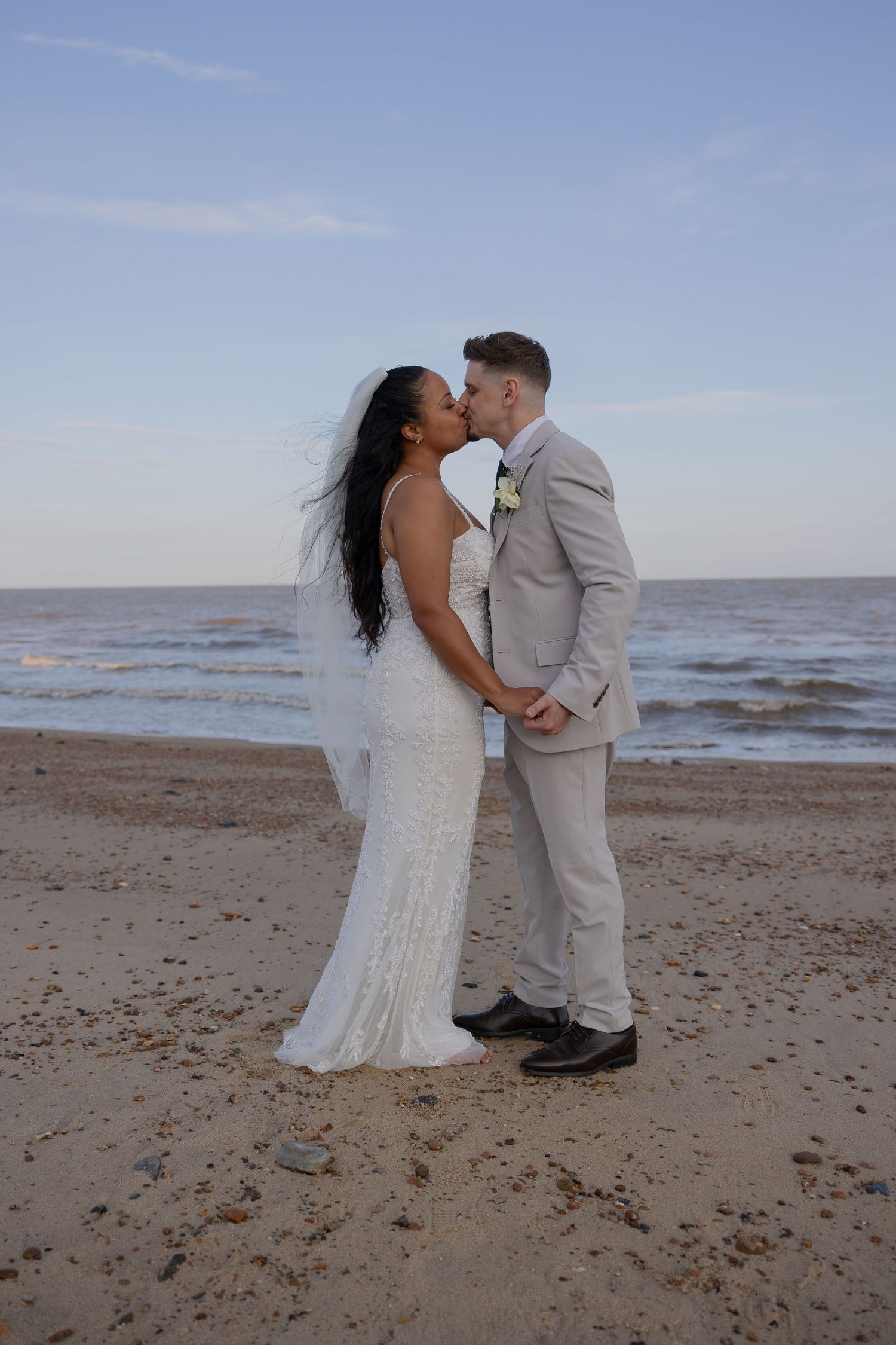 A romantic moment between newlyweds on a serene beach at sunset.