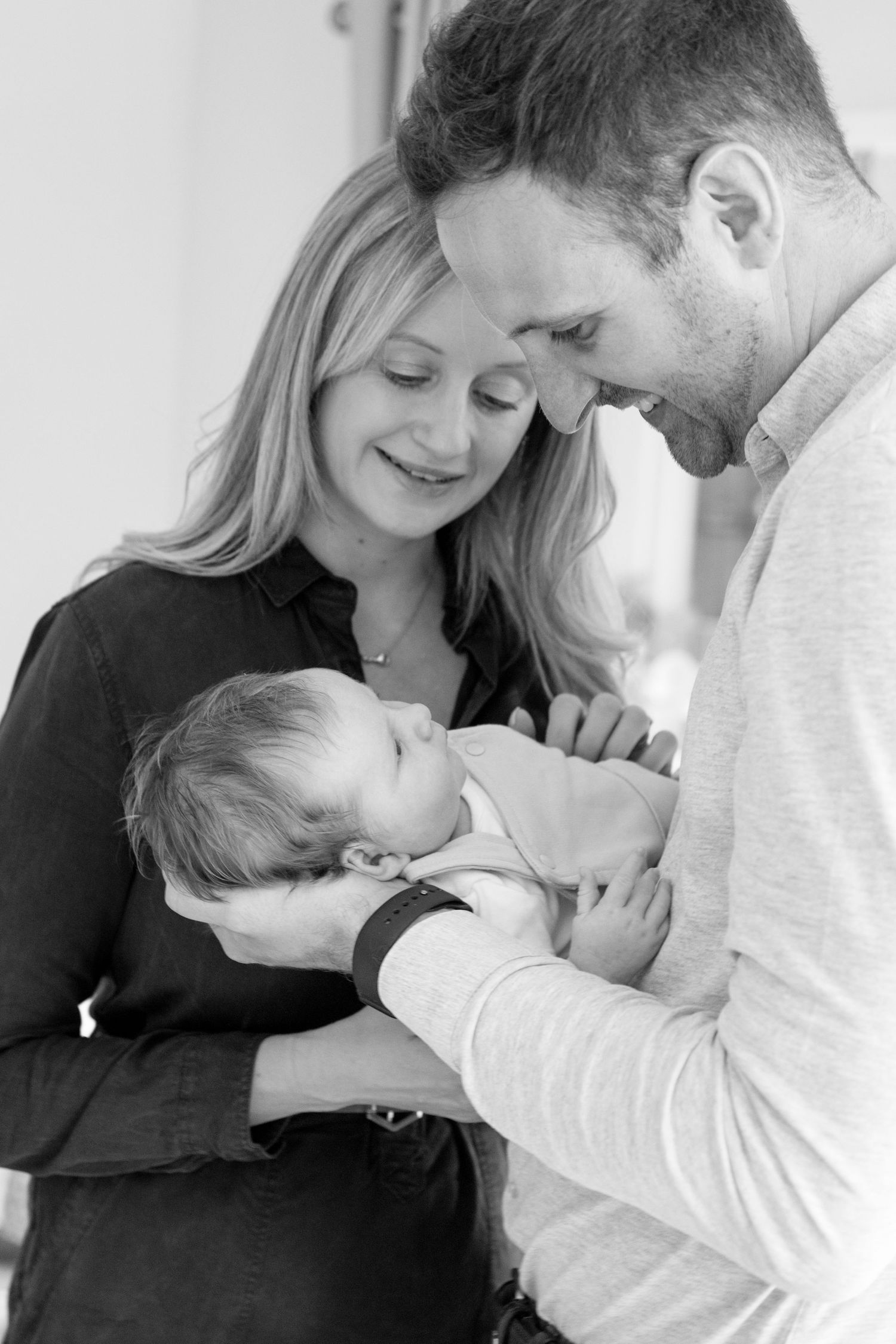A black and white collage shows tender moments between parents and their newborn baby in an intimate photo series.