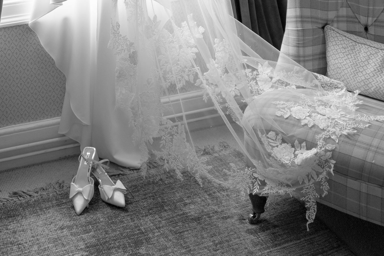 Detail shots of delicate lace wedding dress hem trailing on wooden floor.
