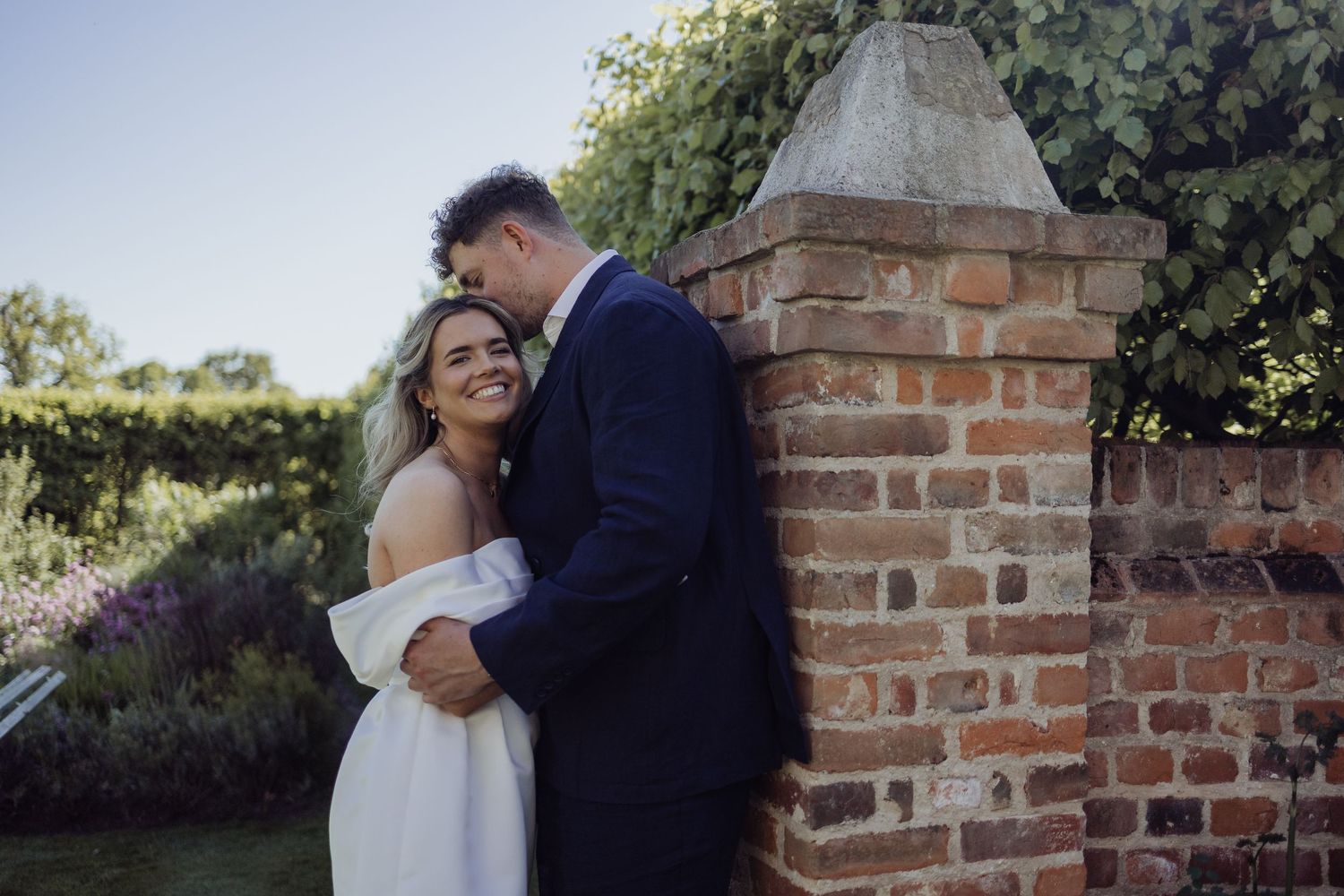 Wedding couple sharing intimate moments near rustic brick wall.