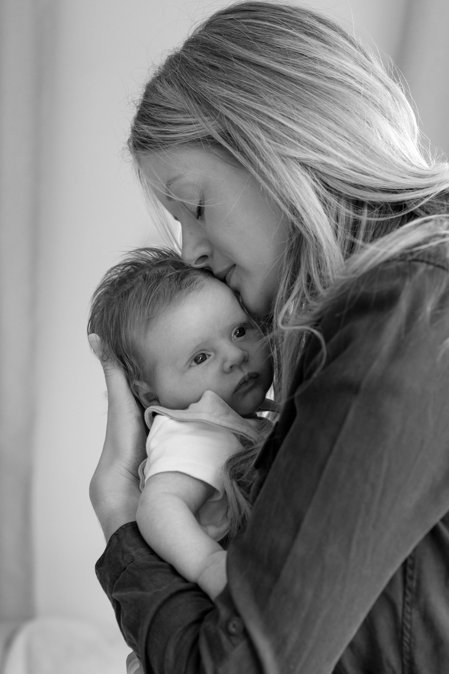 A tender black and white portrait of a mother holding her baby close in a gentle embrace.