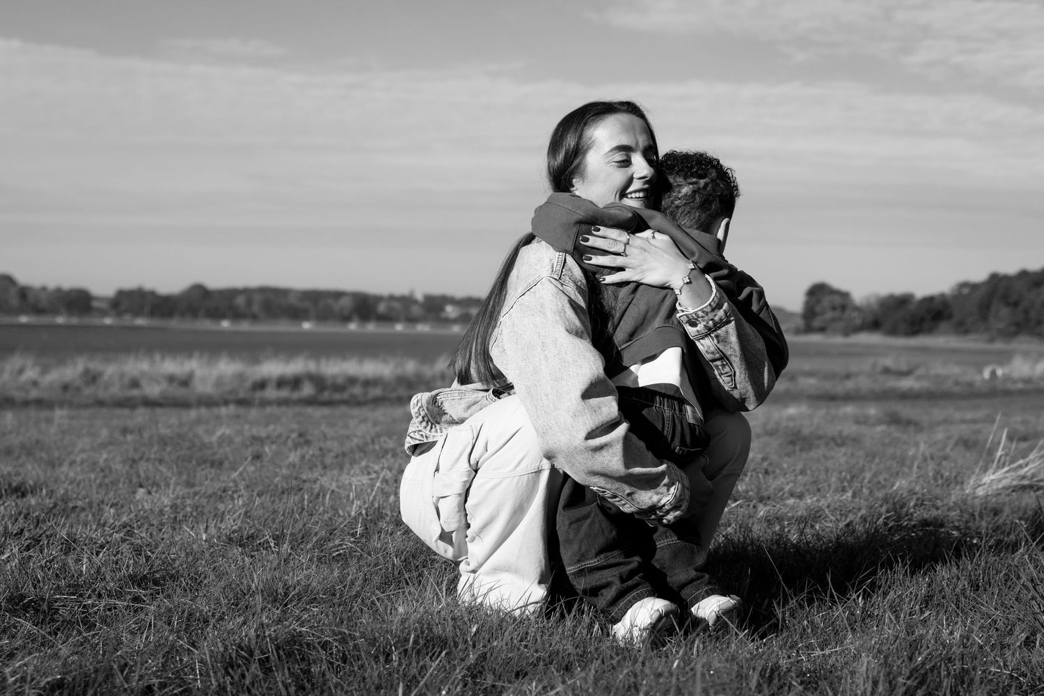 Black and white series showing tender moments between family members in a grassy field.