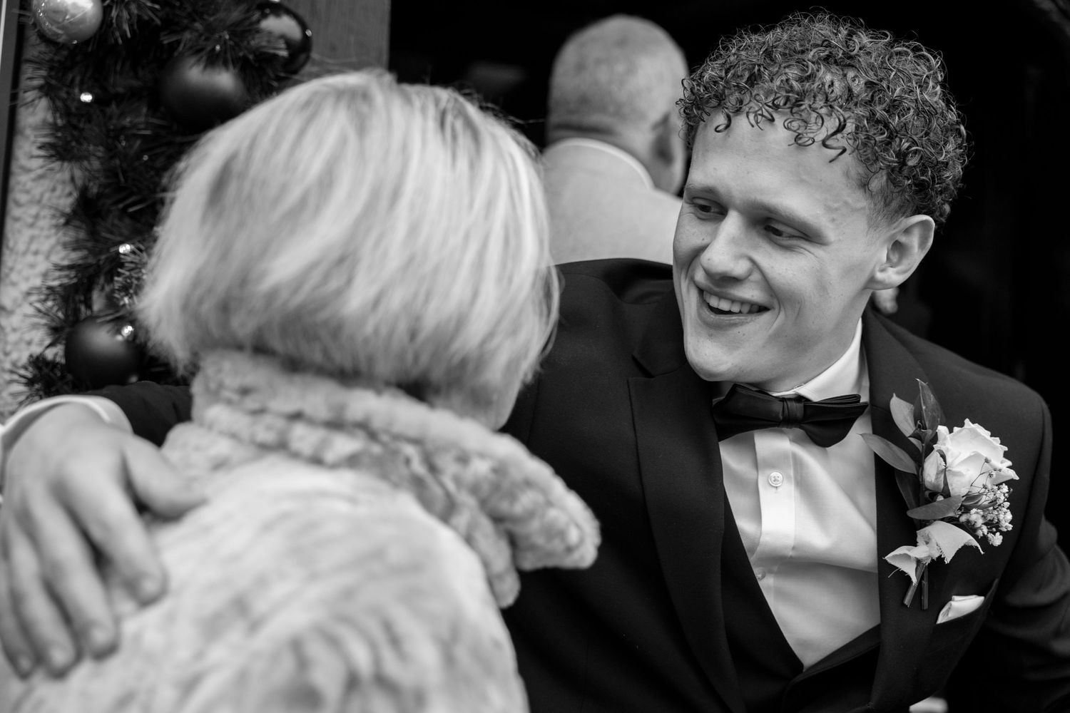 Wedding guests sharing emotional embraces in formal black and white attire.