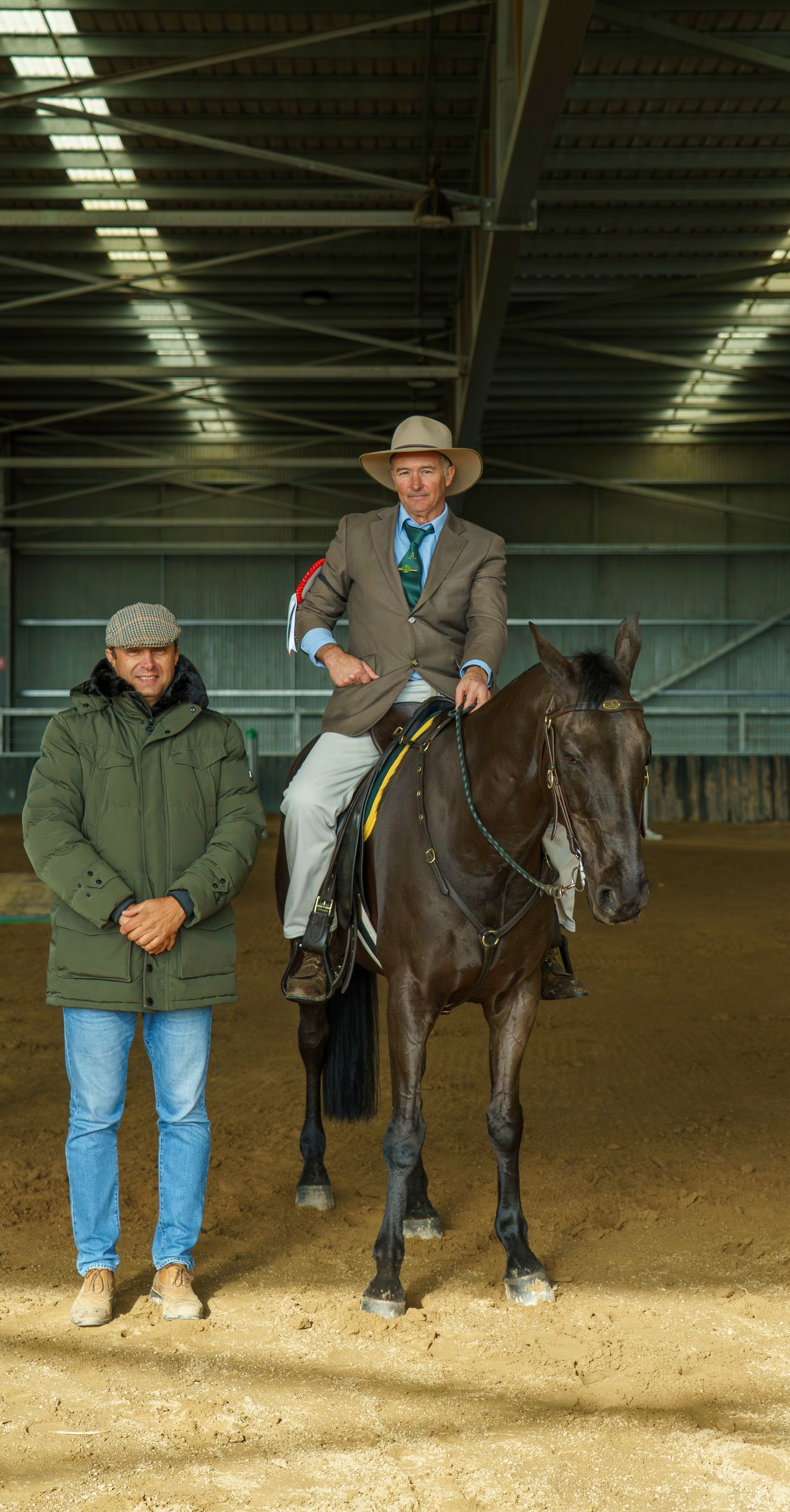 Handlers lead and guide horses during training exercises in an indoor riding arena.