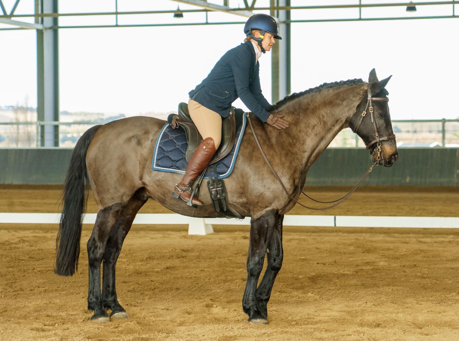 Riders demonstrate proper equestrian form while riding horses in an indoor arena.