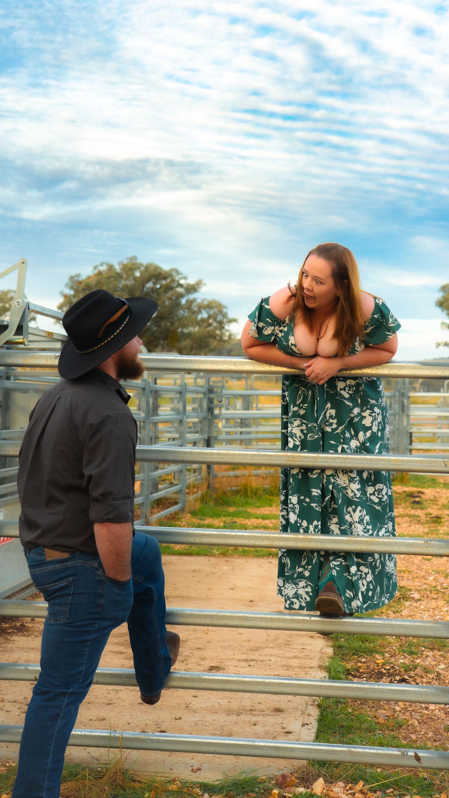 Two people interacting playfully by a white fence on a sunny day.