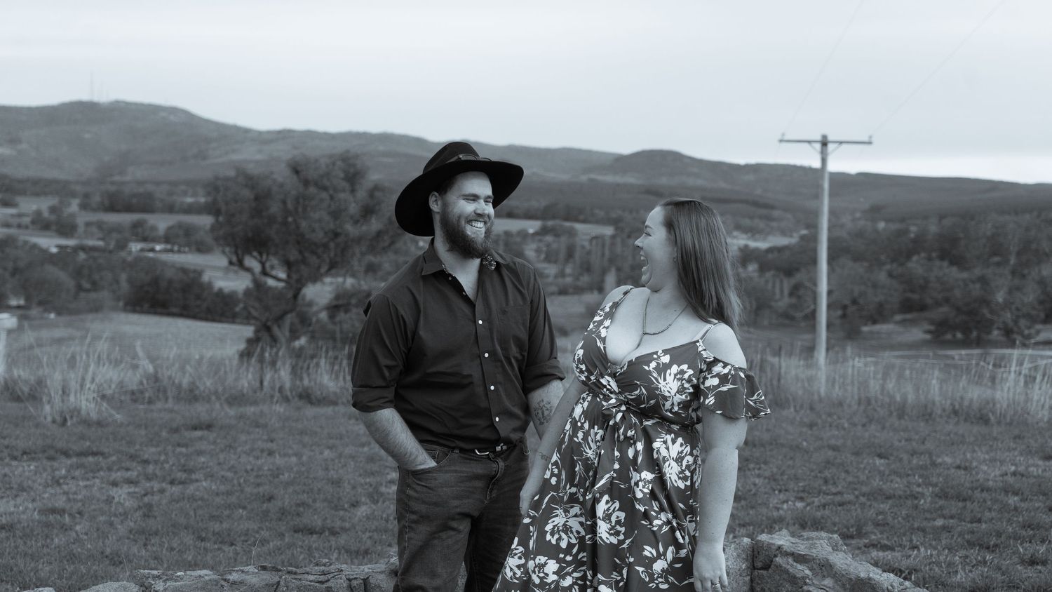 Panoramic black and white view of couple walking through rural landscape.