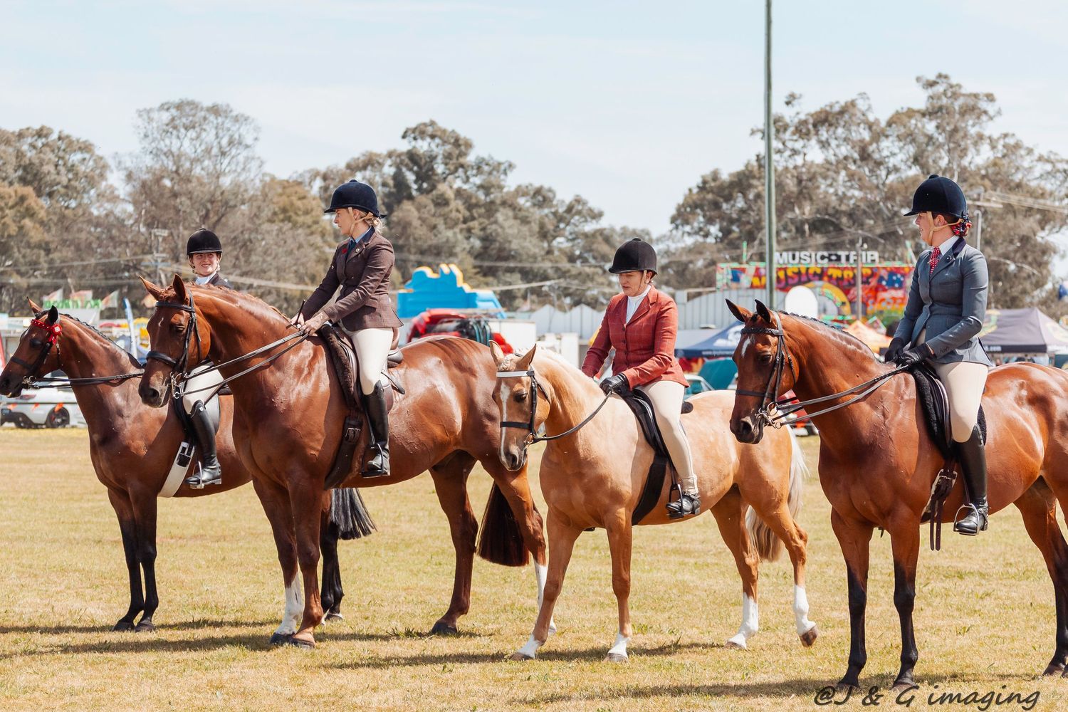 Line of horses and riders standing in formation at an equestrian event on a grassy field.