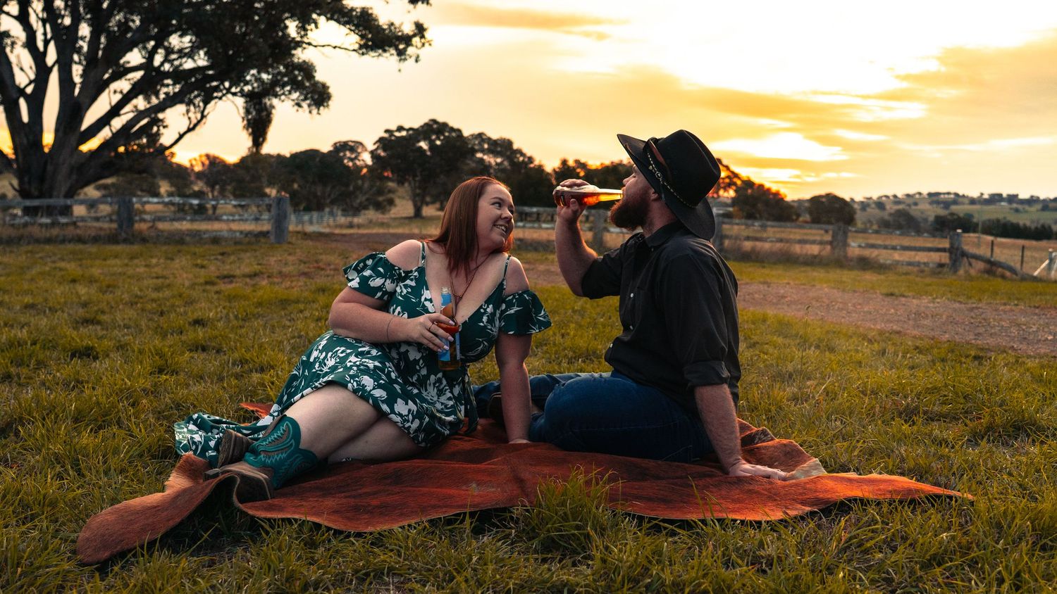 Panoramic sunset view of couple enjoying picnic in countryside.