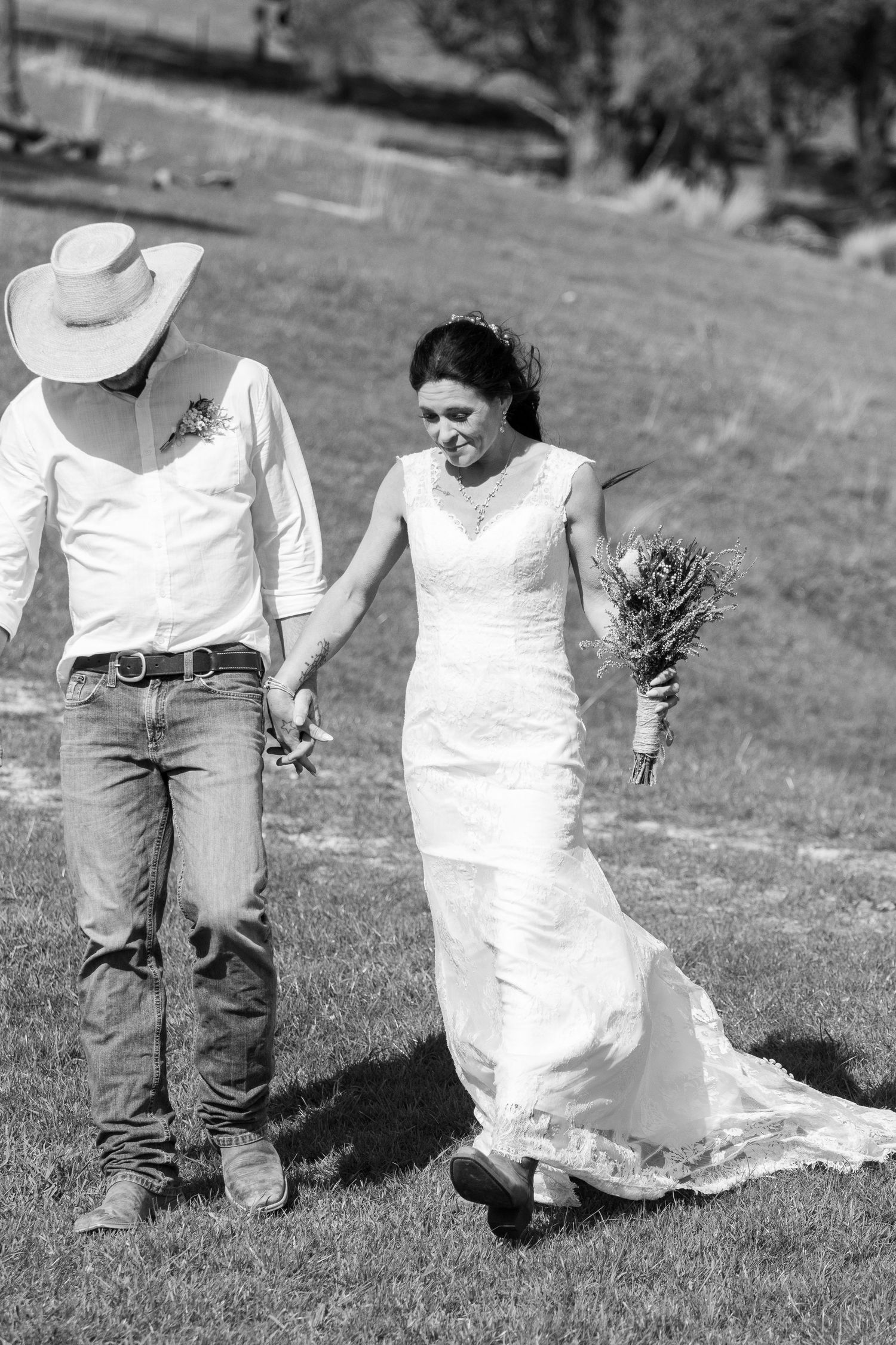 A person in a white wedding dress walking on grass with someone in jeans.