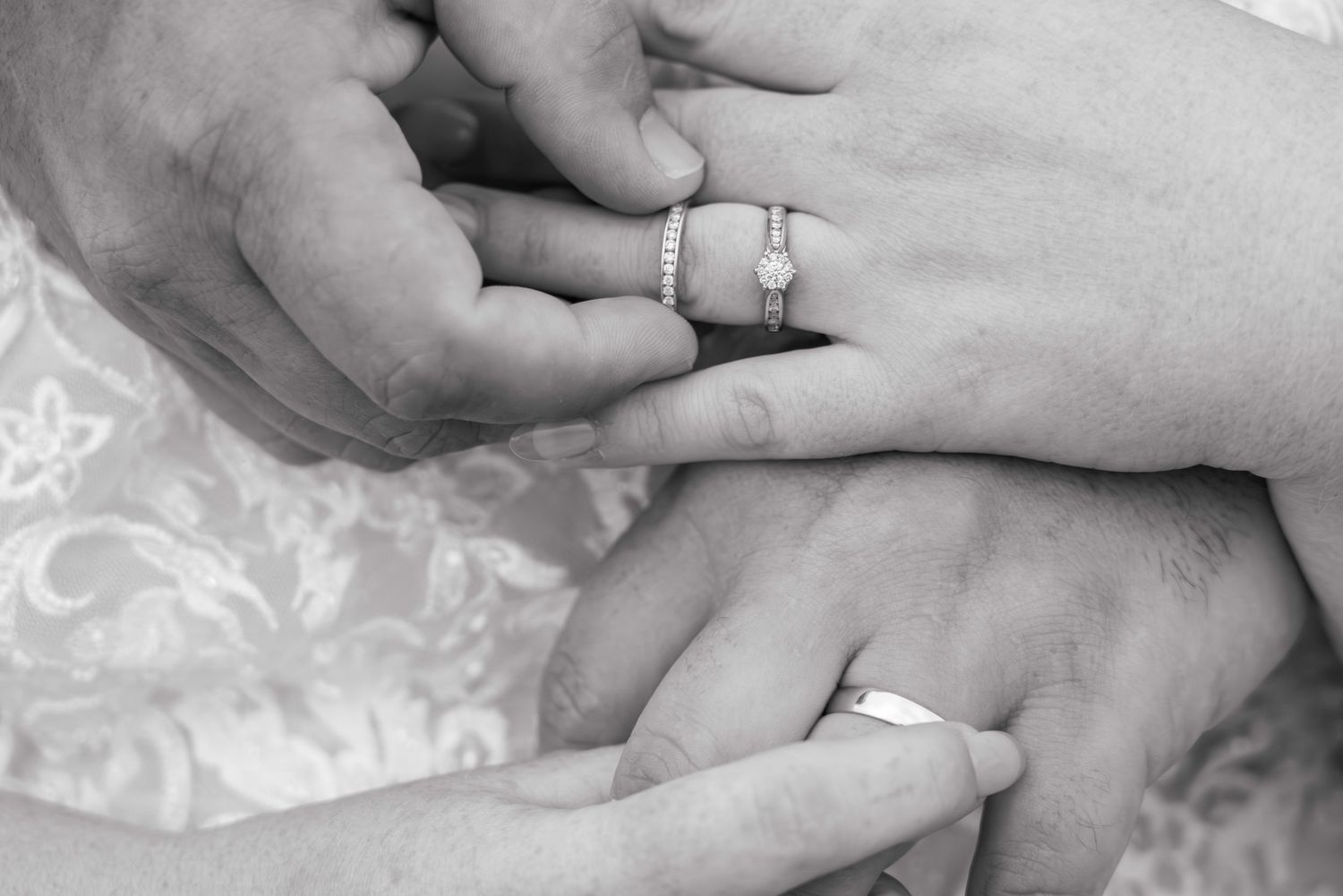 Black and white photo of a couple exchanging wedding rings during a marriage ceremony.