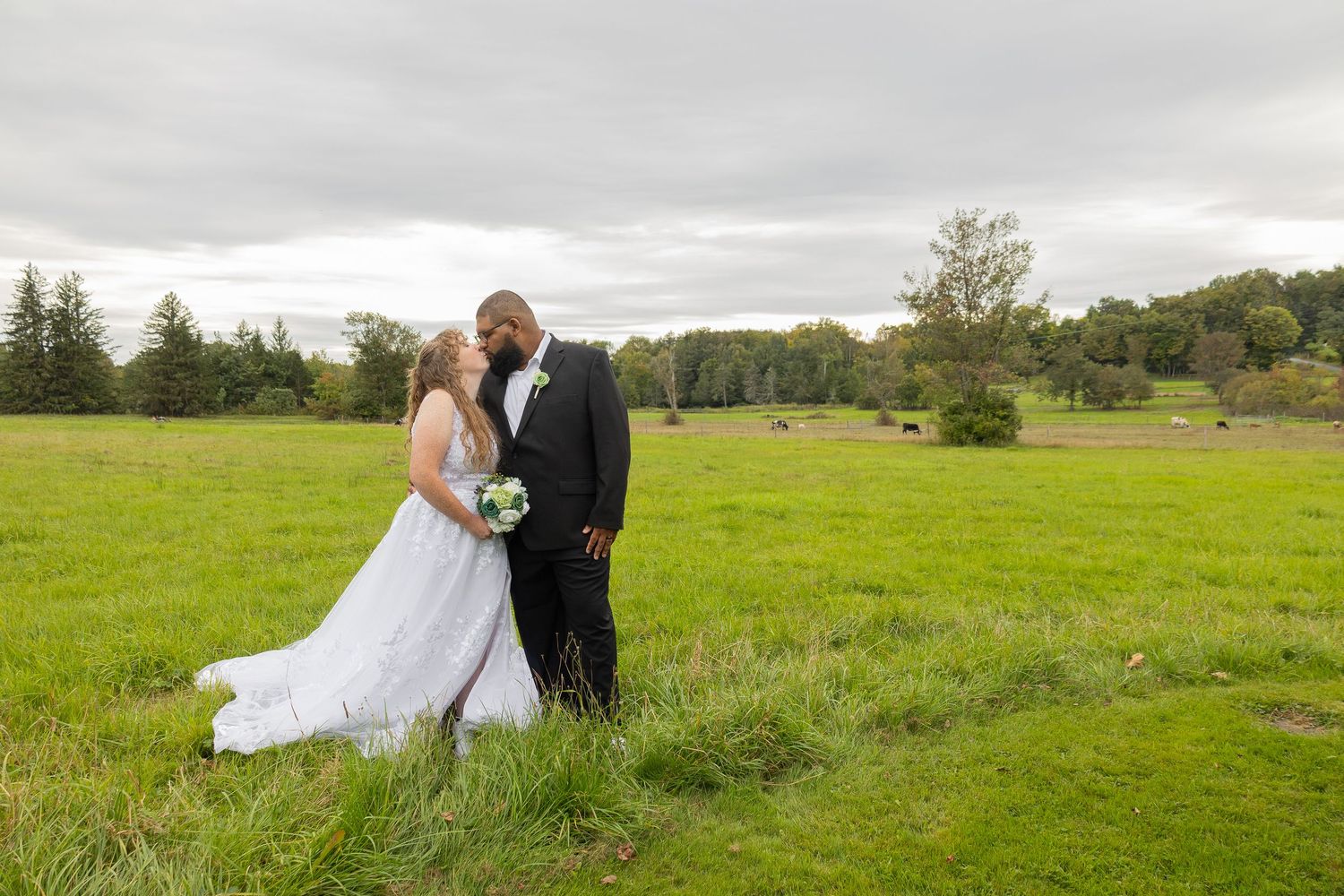 Bride and groom share a romantic moment in a lush green field on their wedding day.