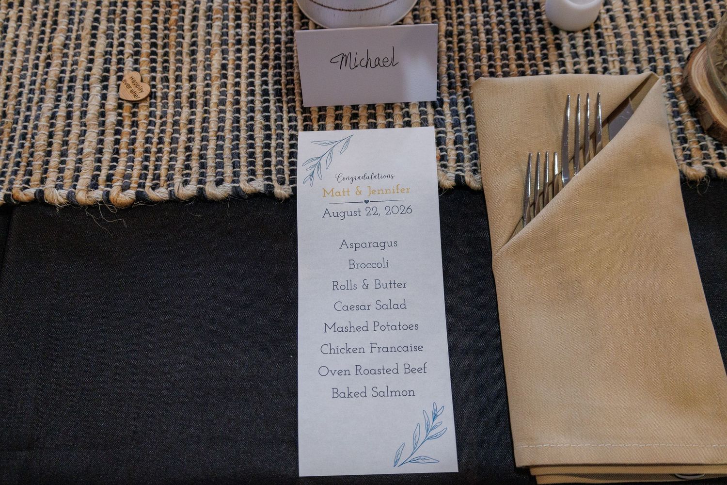 Elegant wedding reception place setting with menu card, name card reading Michael, and gold napkin with silverware.