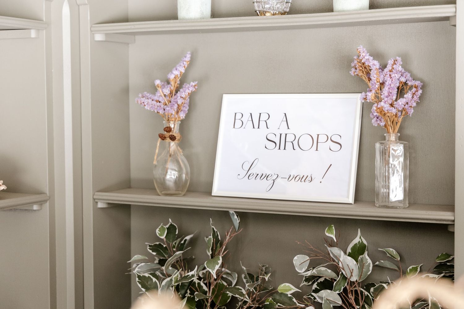 French wedding bar sign reading Bar a Sirops Servez-vous on shelf with pink dried flower arrangements.