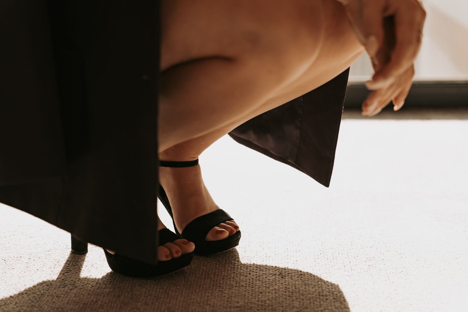 Séance photo boudoir en Isère : élégance et détails raffinés, d'une femme en talons sur un tapis beige.