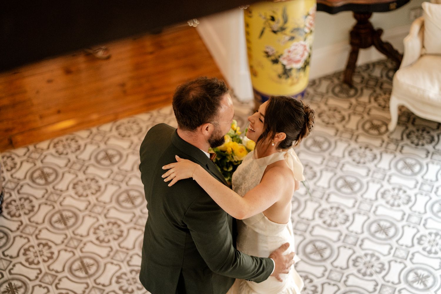 Aerial view of bride and groom embracing on decorative tiled floor during wedding celebration.