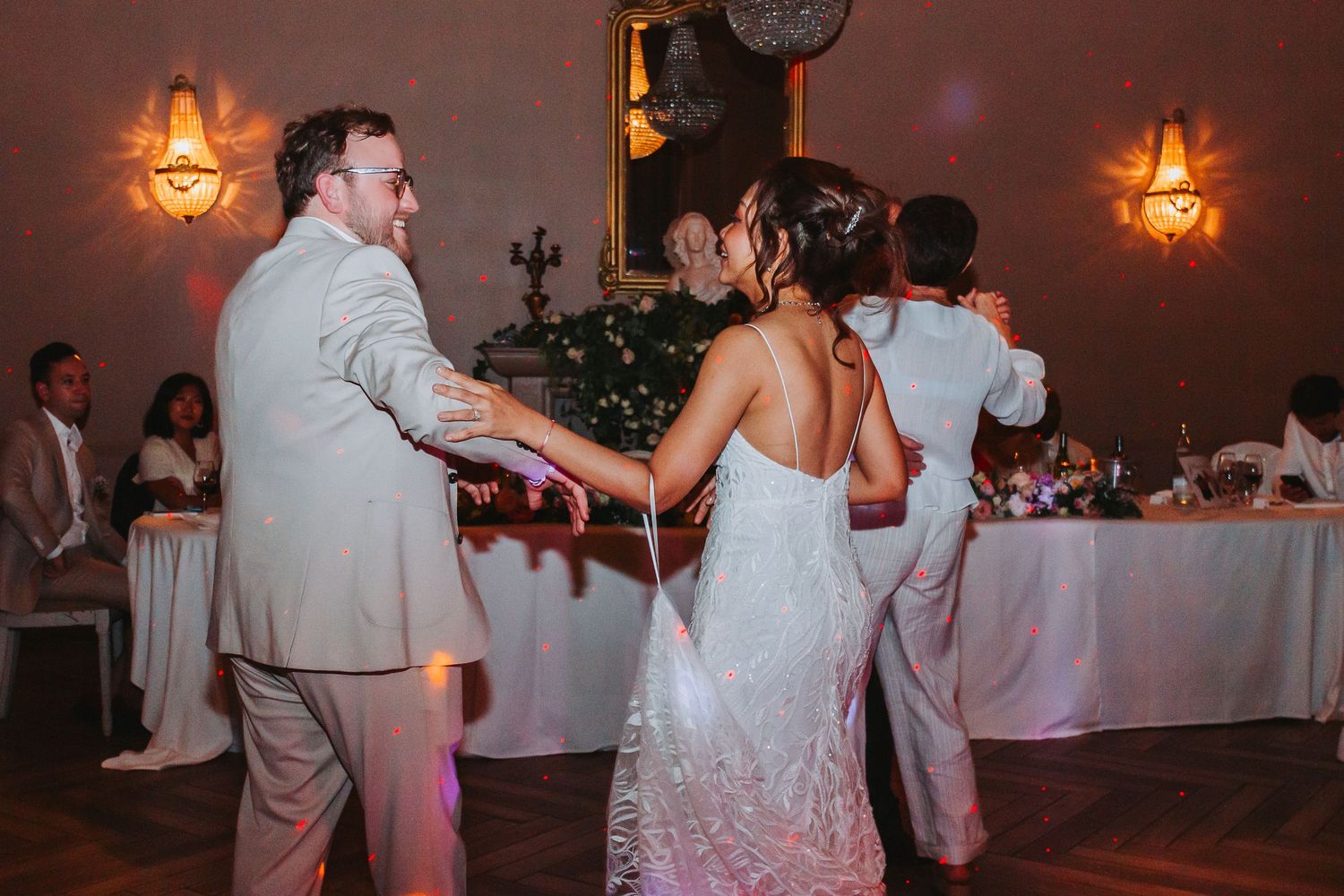 Bride and groom dancing together at elegant wedding reception with warm ambient lighting.