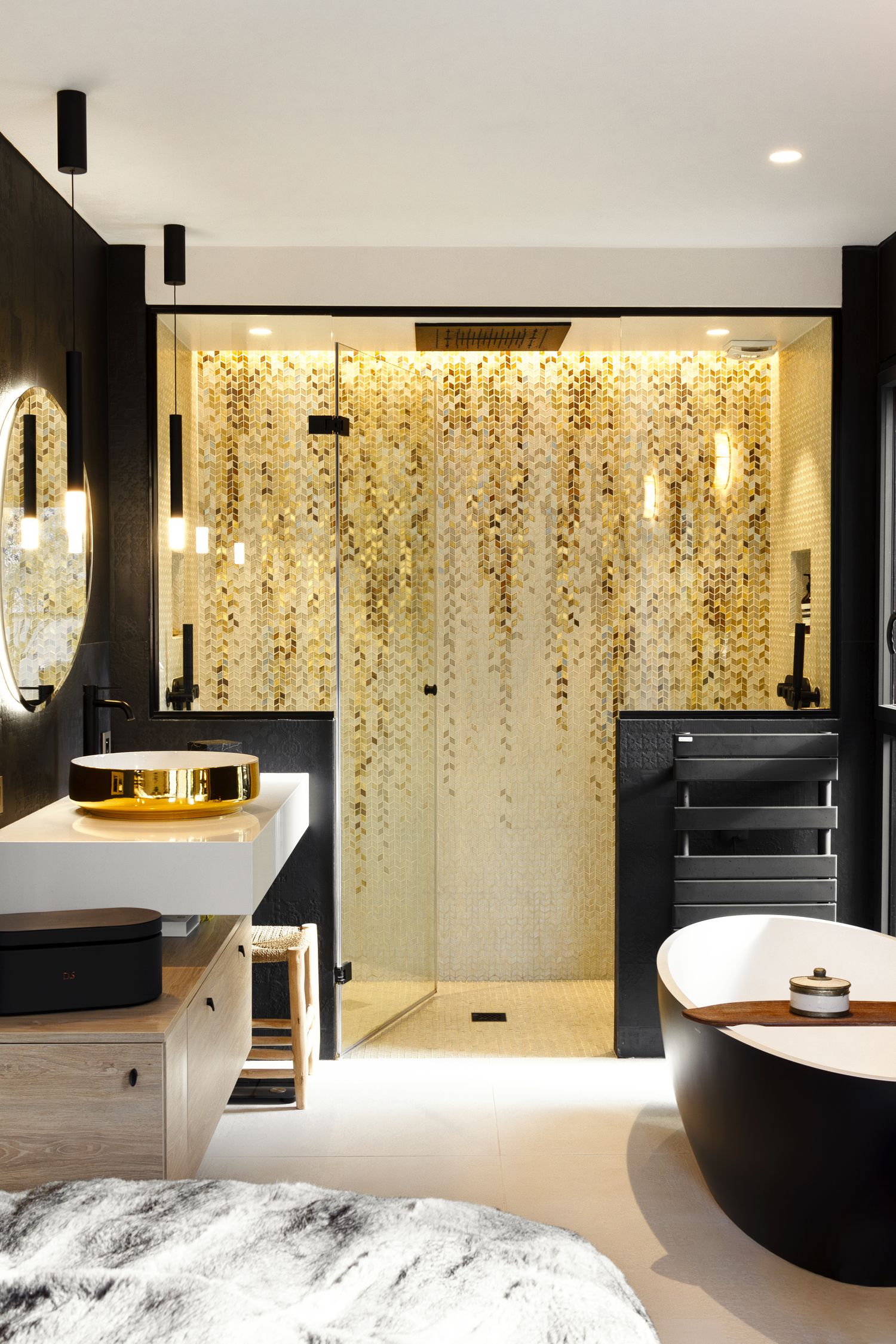 Luxury bathroom with gold mosaic shower, black freestanding tub, and pendant lights.