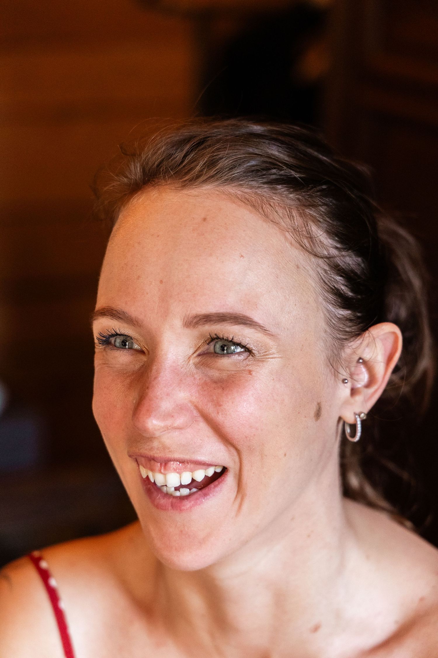 Happy bride with green eyes and freckles laughing during wedding morning preparations indoors.