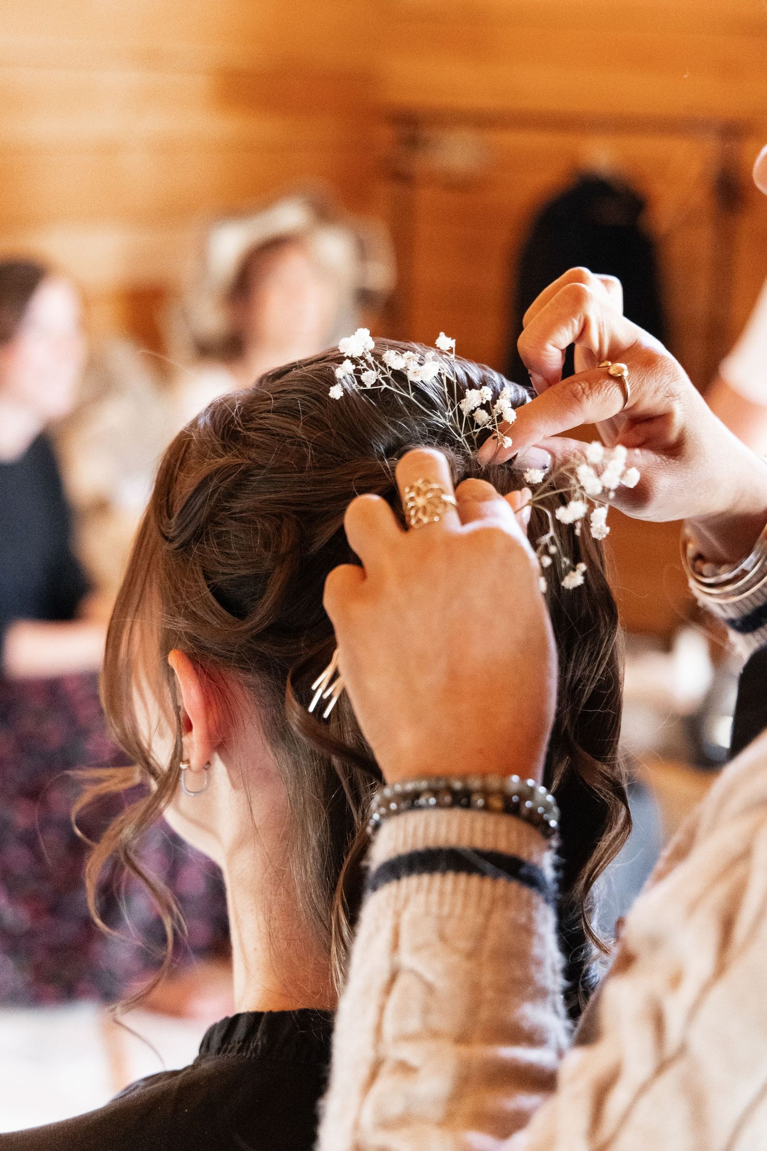 Hairstylist adding small white flowers to a bride's elegant updo hairstyle.