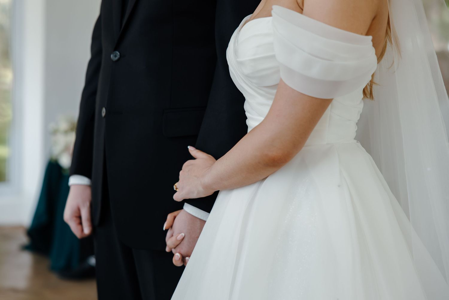 Elegant wedding couple shares an intimate moment in white formal attire.