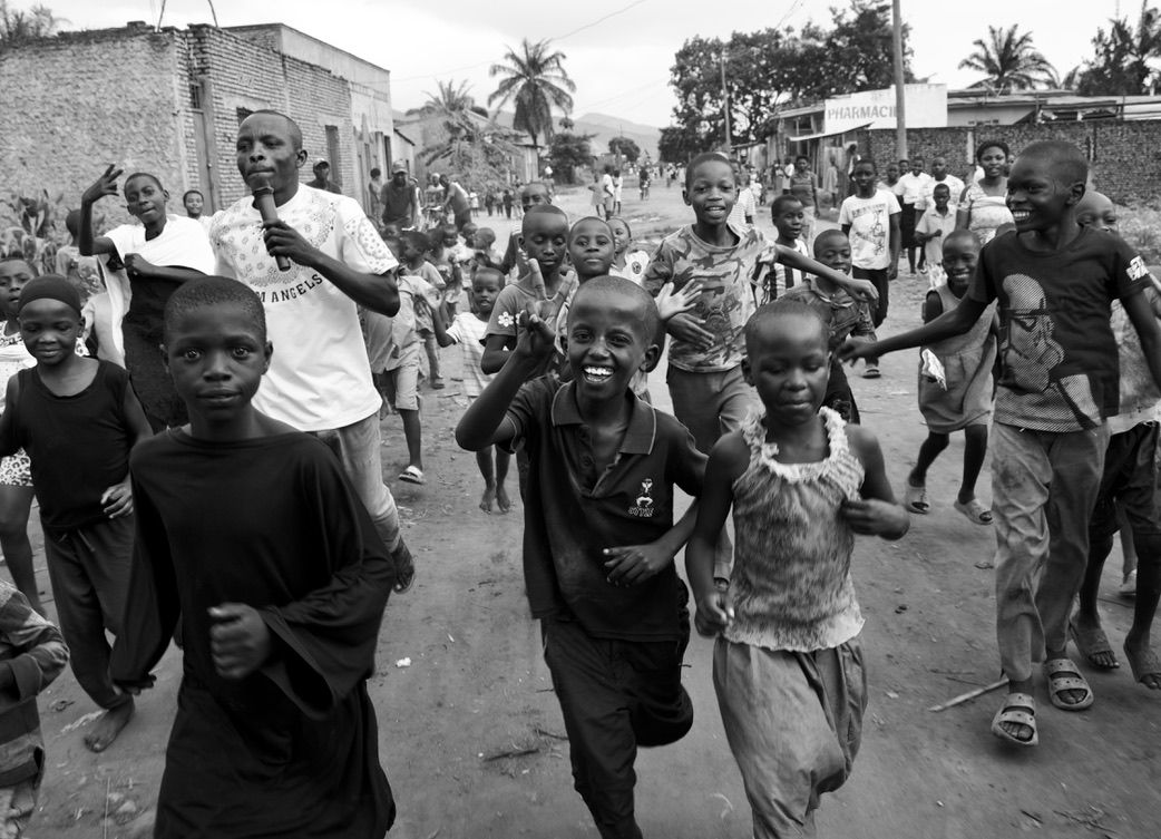 Children running and playing on a busy urban street in black and white photo.