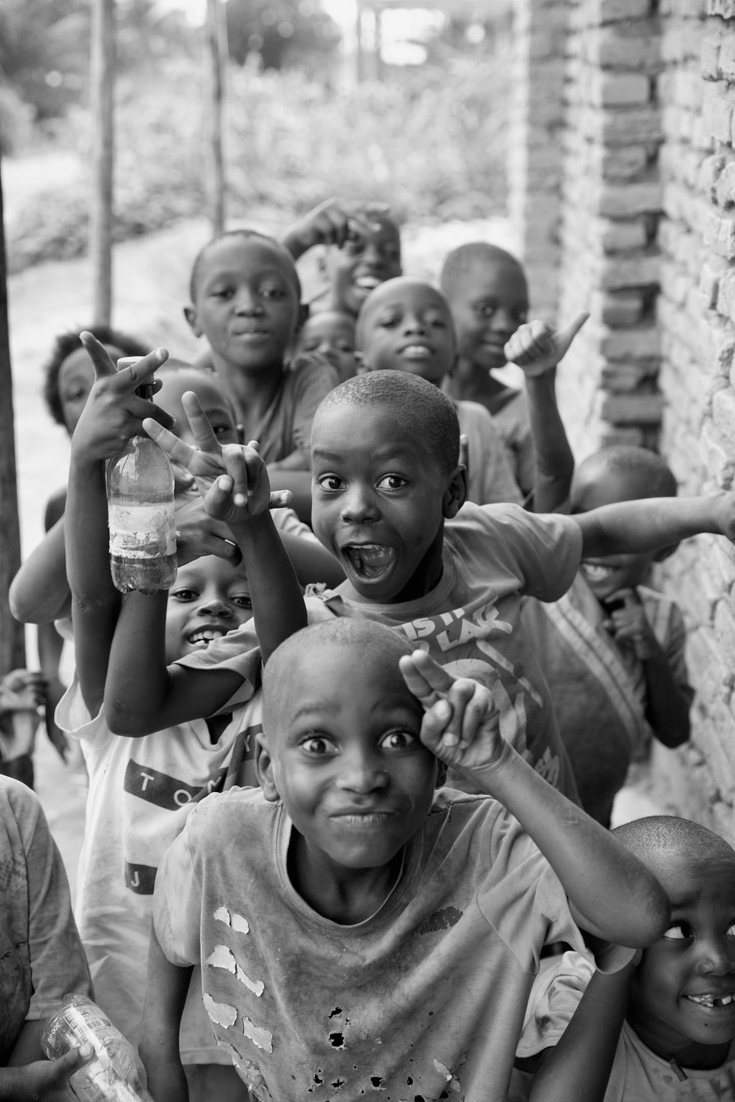 Group of joyful African children posing and making gestures for a black and white photo.