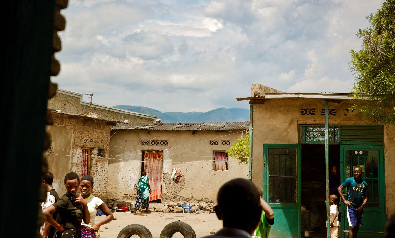 Children playing in African village street with mountains visible in cloudy background.