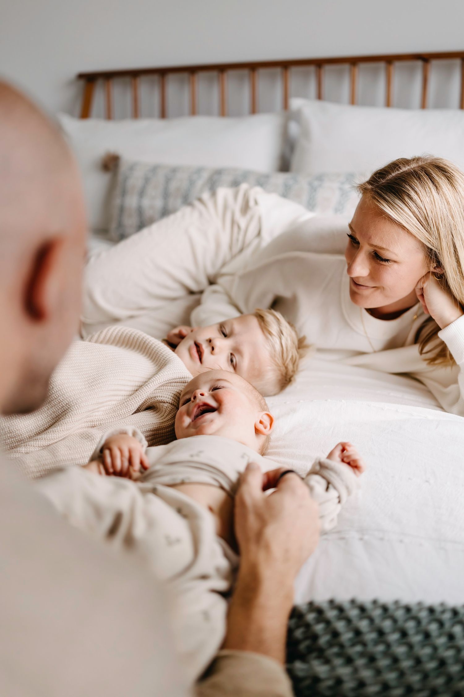 Playful family interactions on a cozy bed in warm neutral tones.